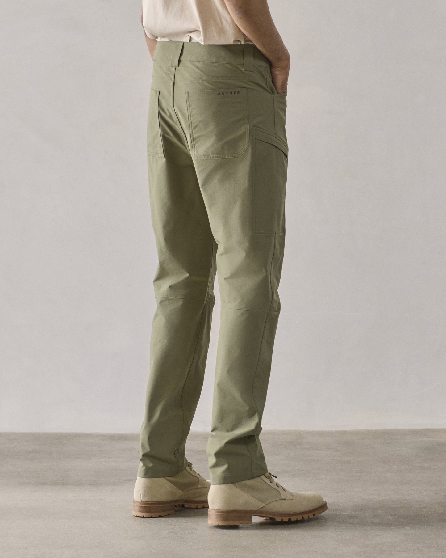 Rear 3/4 lower-body view of man wearing Adventure Pant in Fern Green from AETHER Apparel.