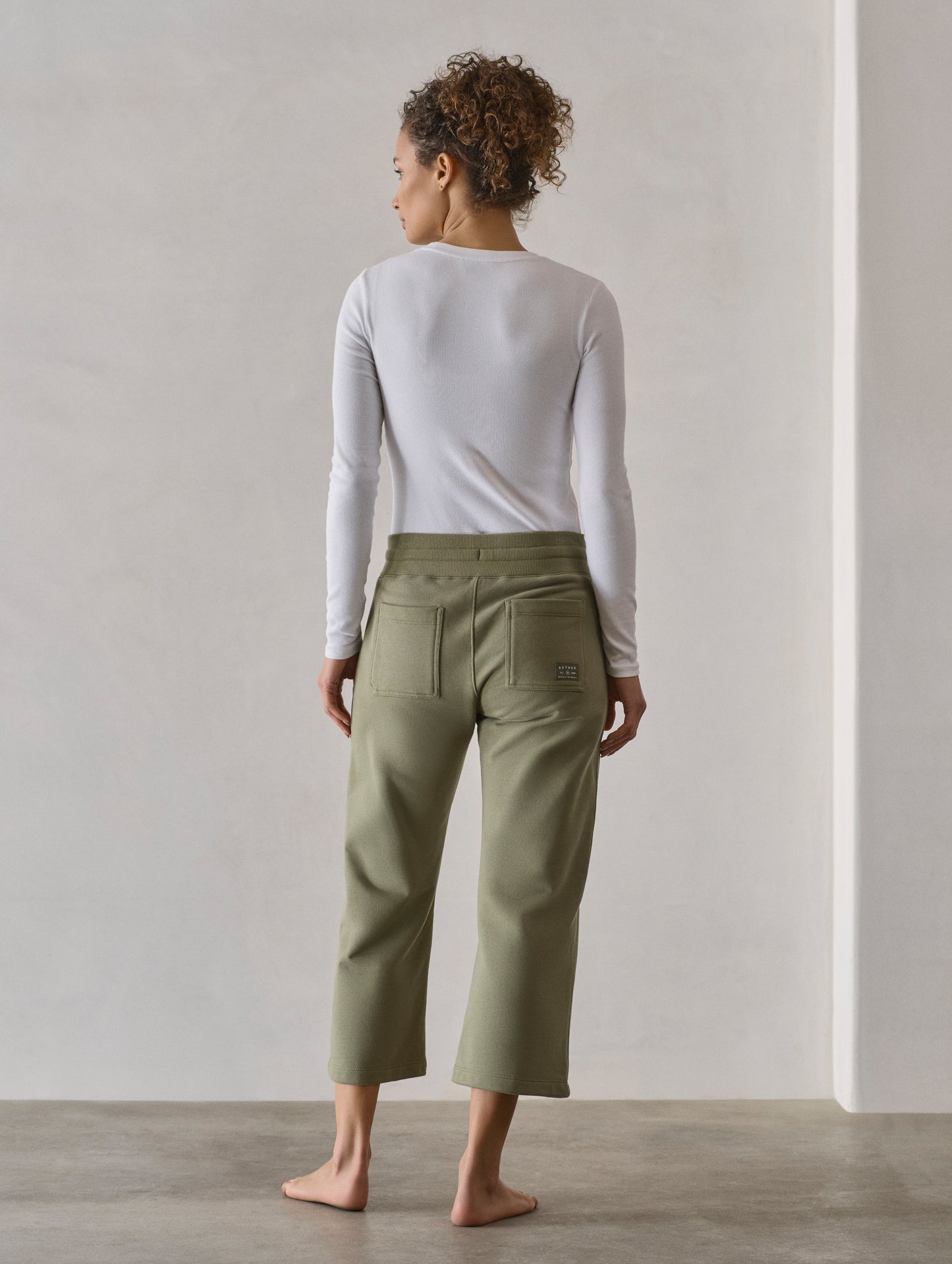 Rear full-body view of woman wearing W Osa Cropped Sweatpant in Fern Green from AETHER Apparel.