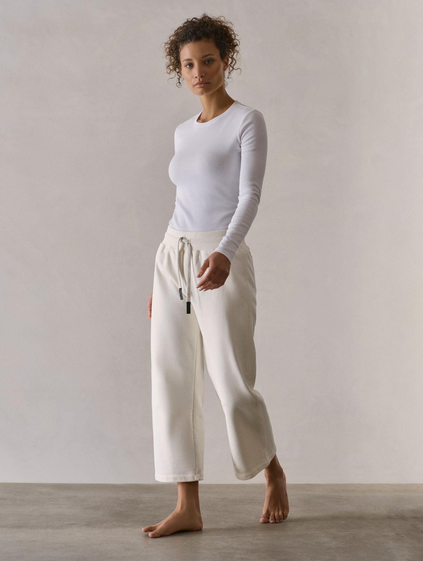 Front 3/4 full-body view of woman wearing W Osa Cropped Sweatpant in Winter White from AETHER Apparel.
