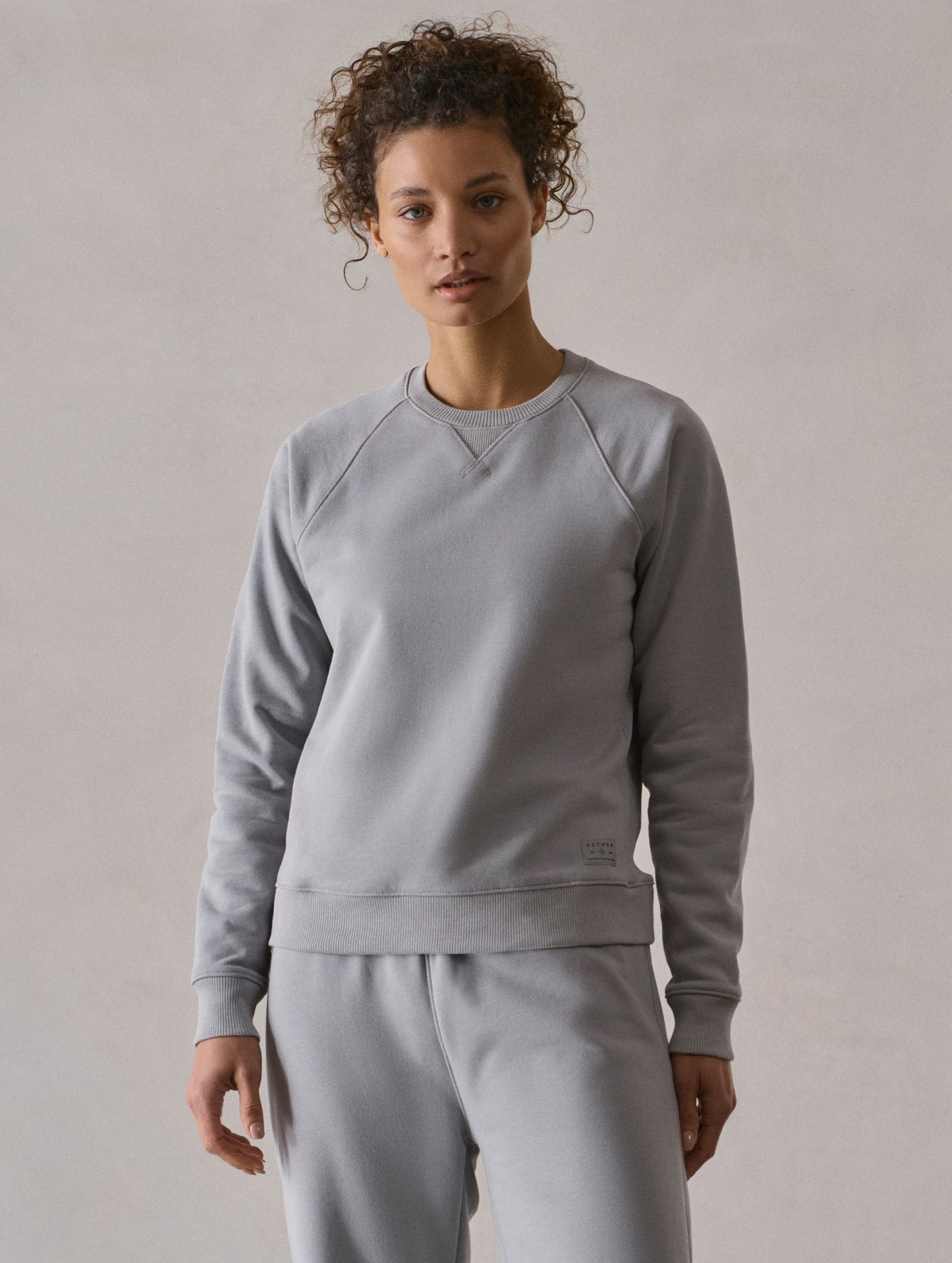 Front full-body view of woman wearing W Osa Raglan Sweatshirt in Sky Grey from AETHER Apparel.