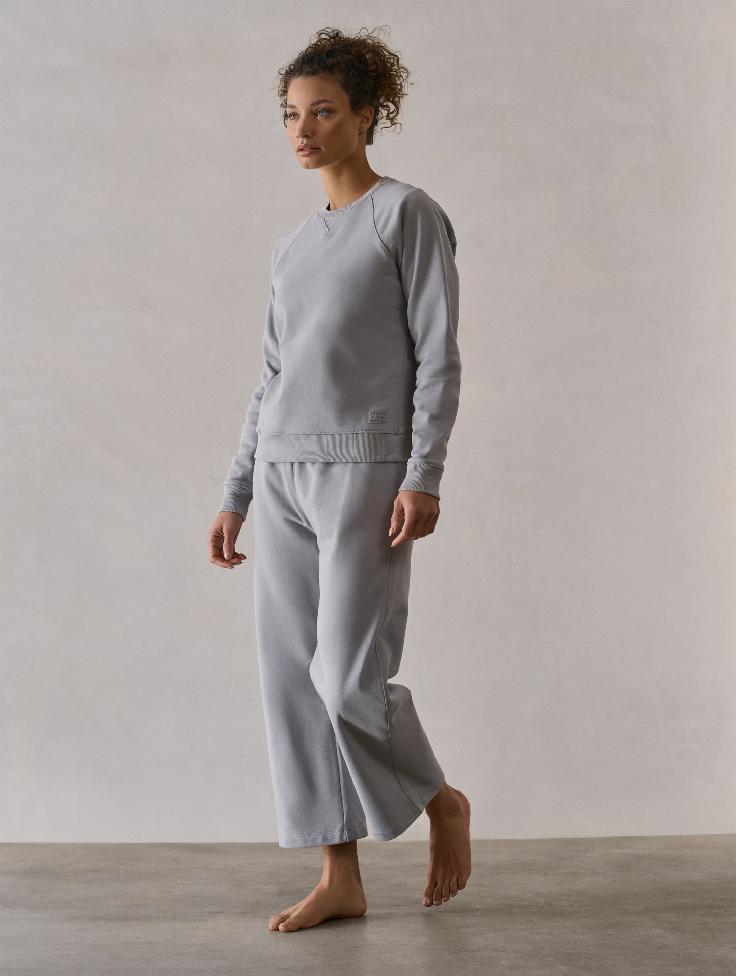 Front 3/4 full-body view of woman wearing W Osa Raglan Sweatshirt in Sky Grey from AETHER Apparel.