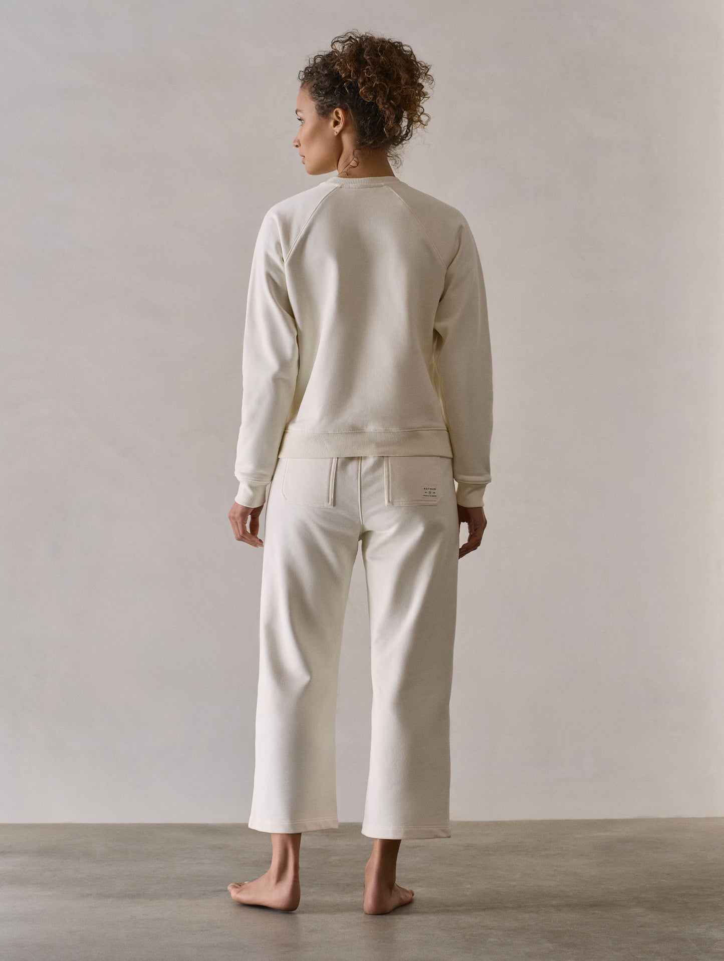Rear full-body view of woman wearing W Osa Raglan Sweatshirt in Winter White from AETHER Apparel.