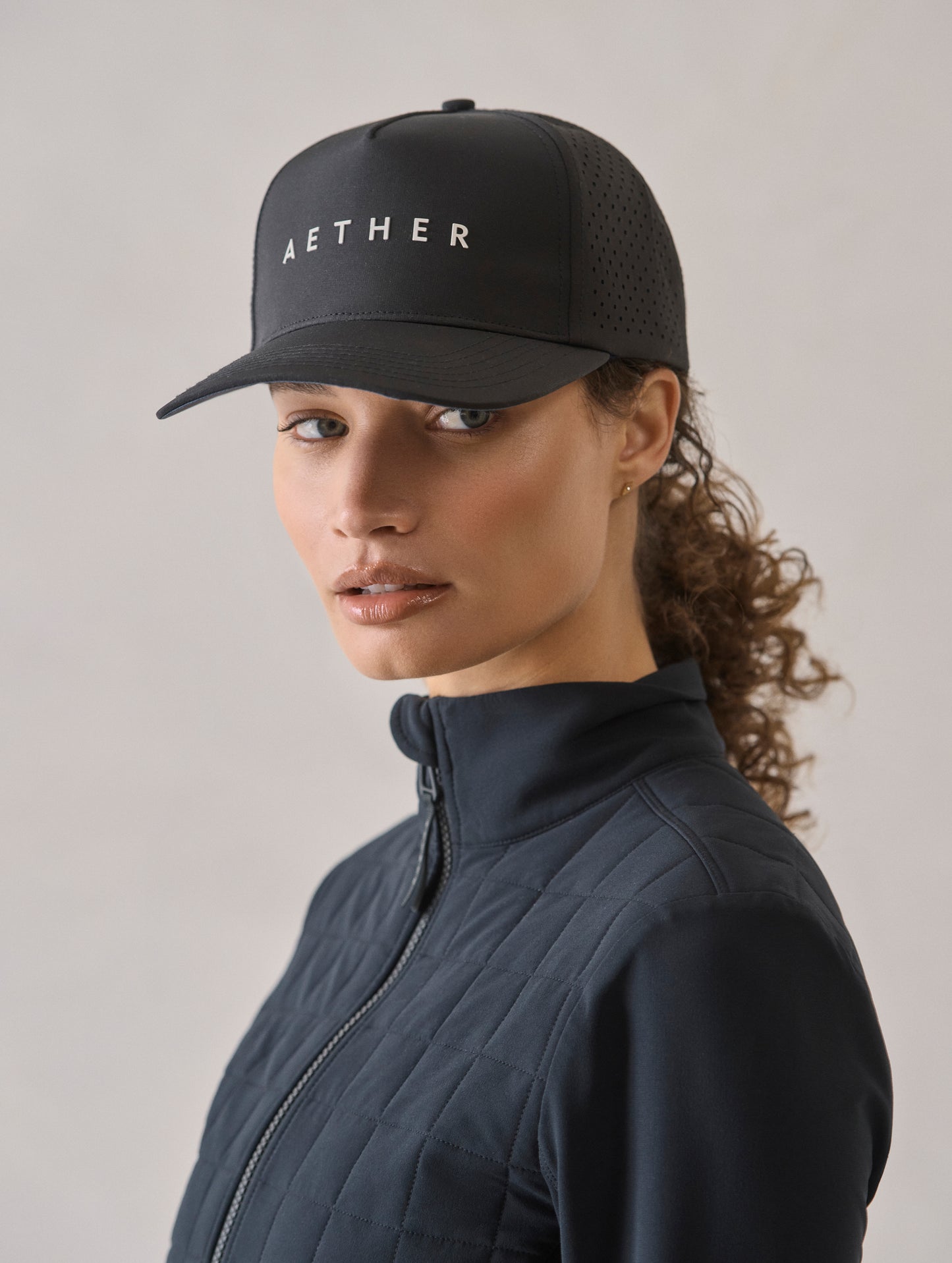 Front 3/4 view of woman wearing Adventure Mesh Hat in Onyx Black from AETHER Apparel.