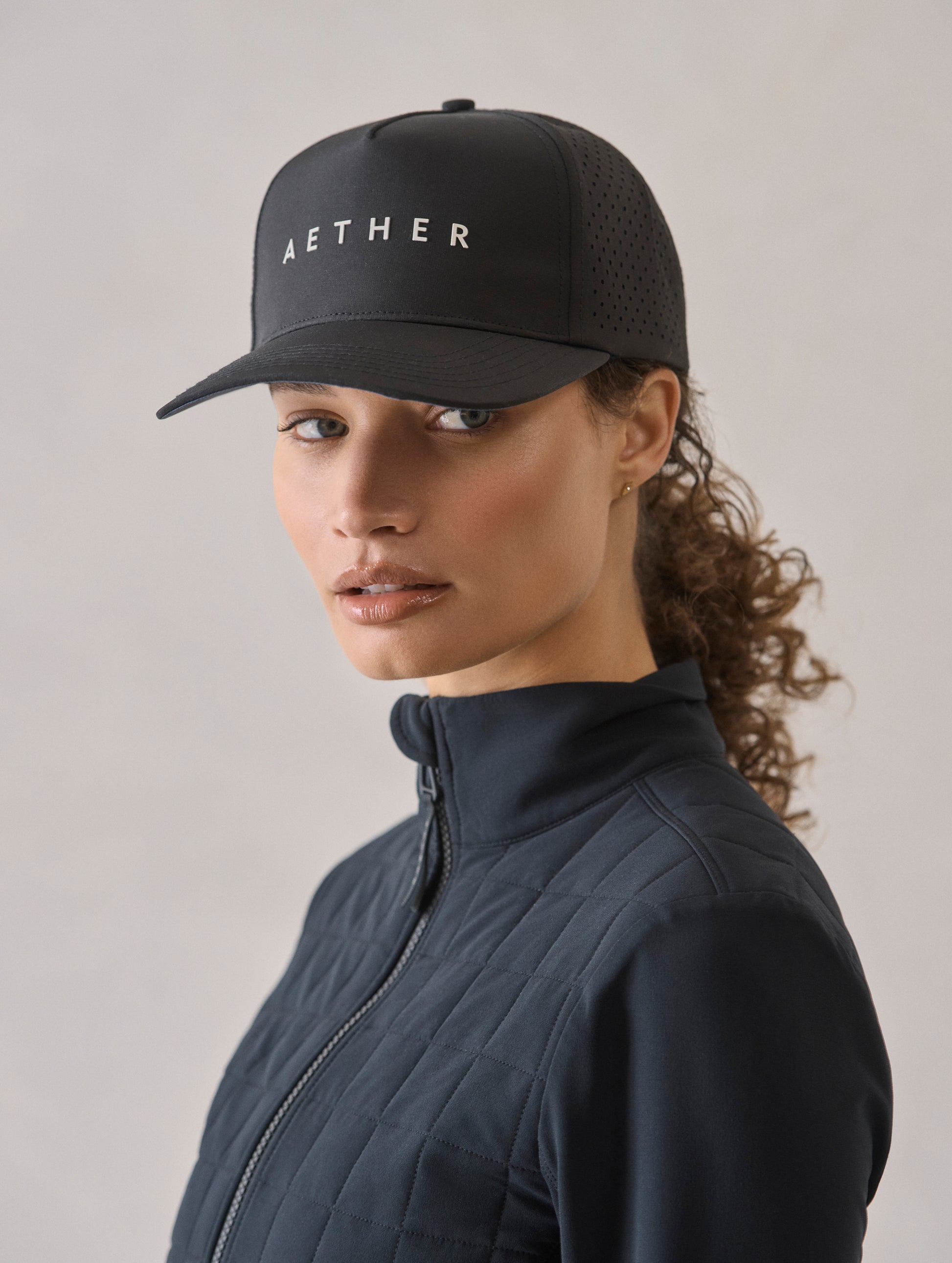 Front 3/4 view of woman wearing Adventure Mesh Hat in Onyx Black from AETHER Apparel.