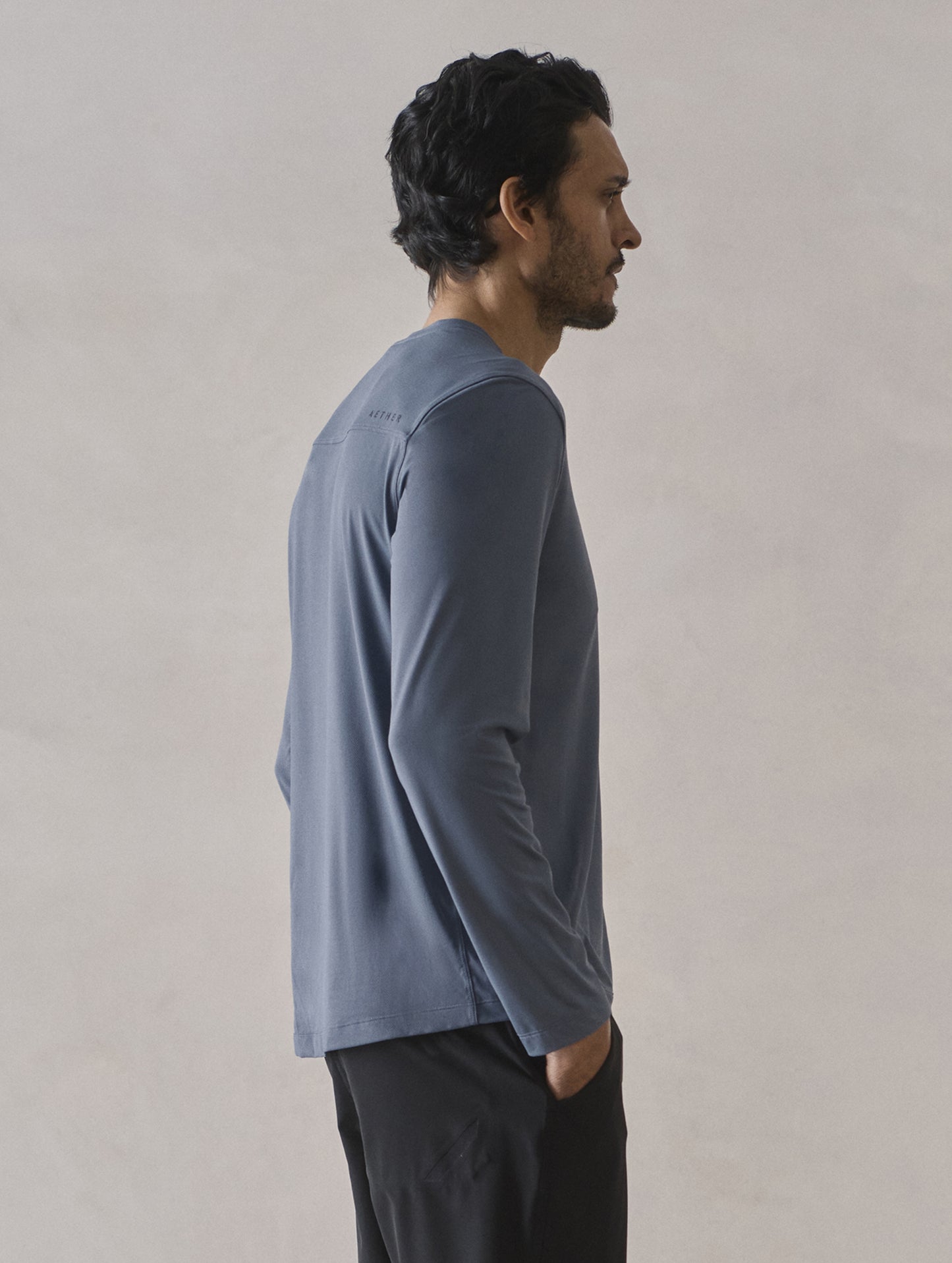 Rear 3/4 upper-body view of man wearing Adventure Performance Long-Sleeve Tee in Portal Blue from AETHER Apparel.