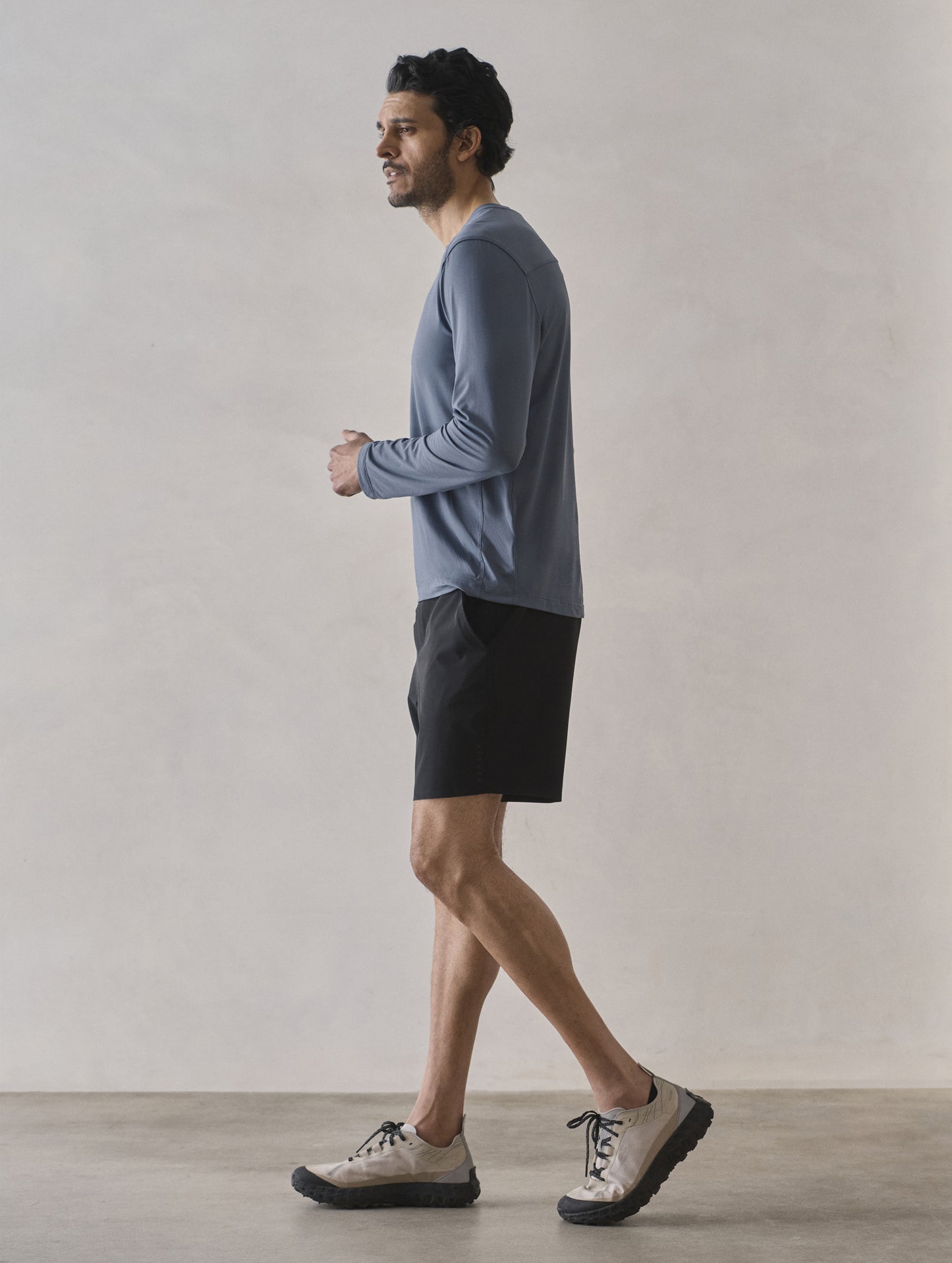 Side profile full-body view of man wearing Adventure Performance Long-Sleeve Tee in Portal Blue from AETHER Apparel.