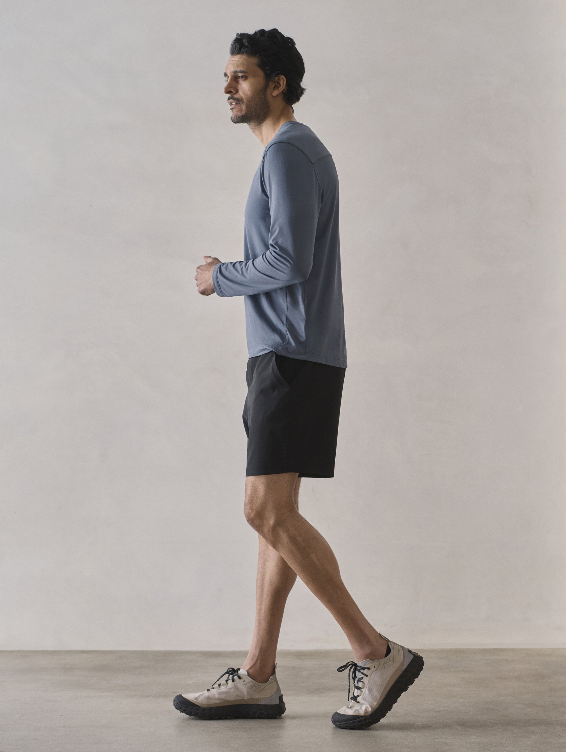 Side profile full-body view of man wearing Adventure Performance Long-Sleeve Tee in Portal Blue from AETHER Apparel.