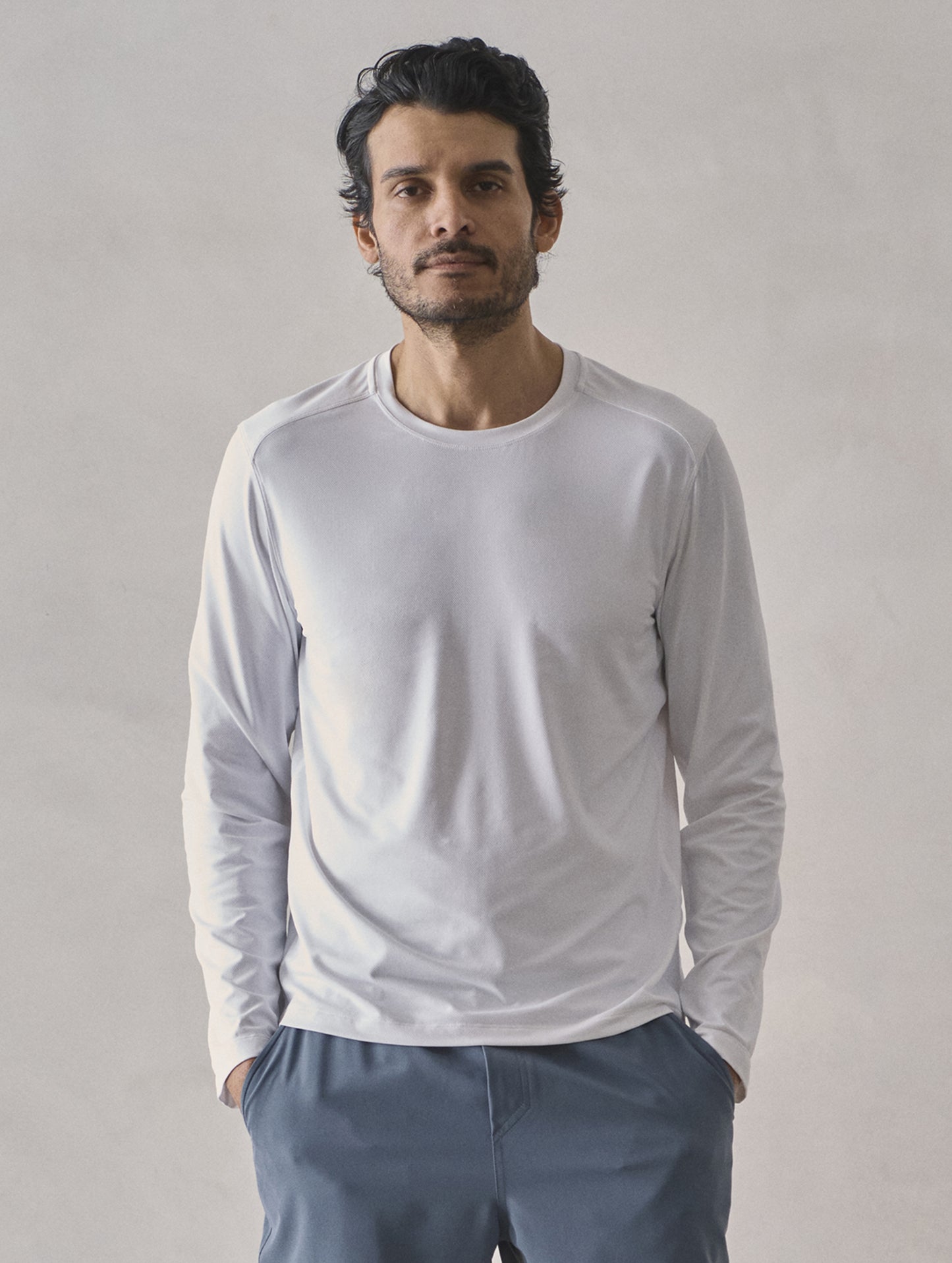 Front upper-body view of man wearing Adventure Performance Long-Sleeve Tee in White from AETHER Apparel.
