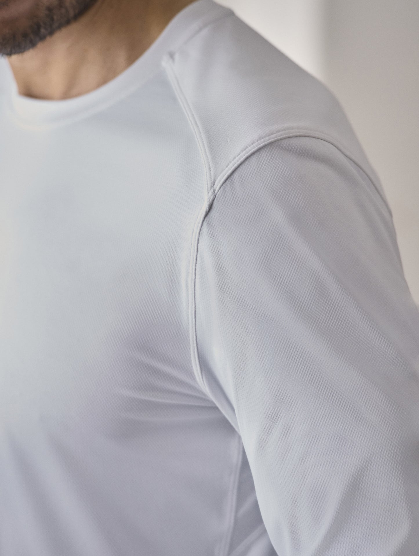 Closeup detailed view of forward shoulder seam on the Adventure Performance Long-Sleeve Tee in White from AETHER Apparel.
