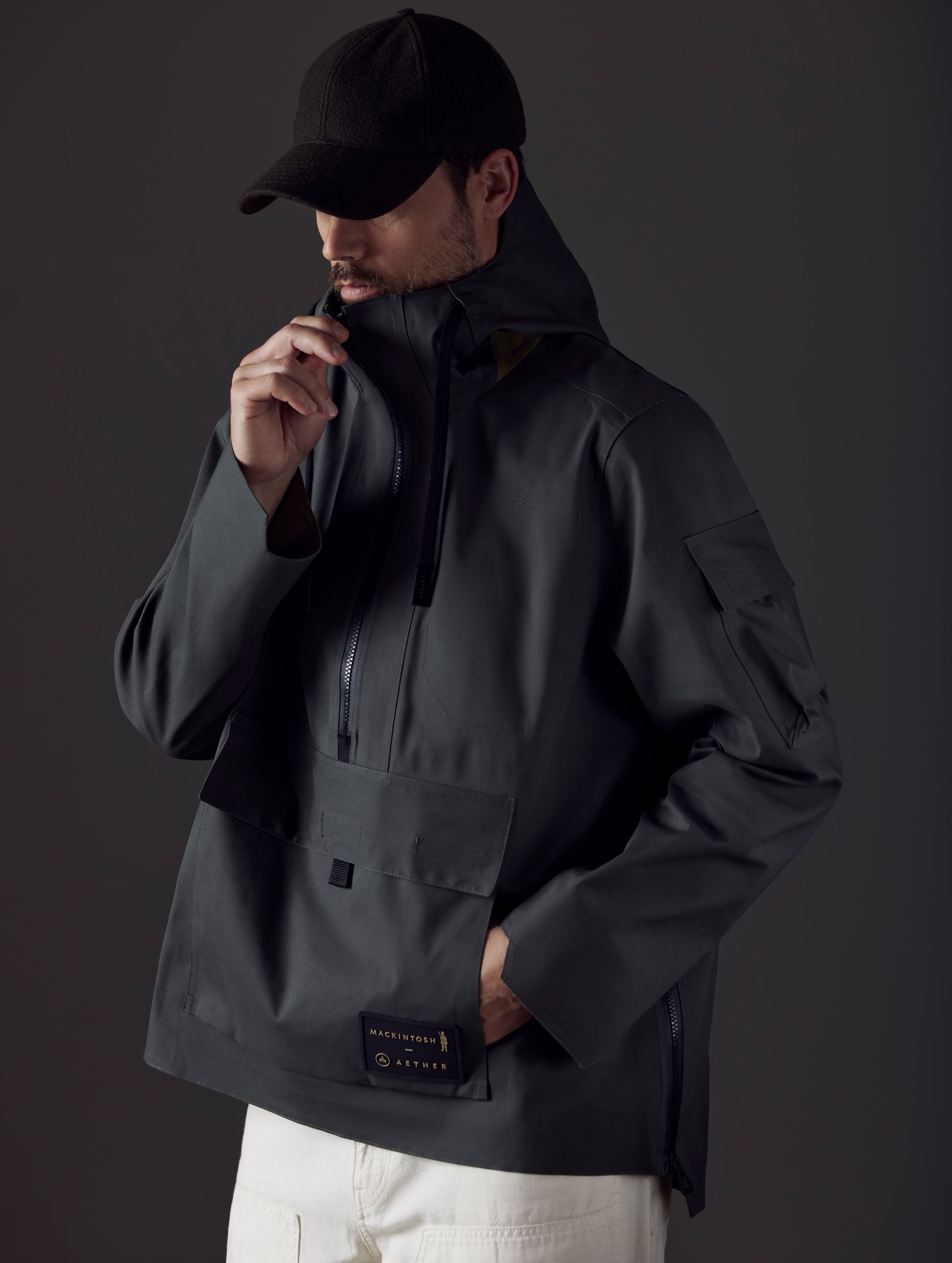 Front body view of man wearing AETHER + Mackintosh Field Anorak in Dark Bottle black.