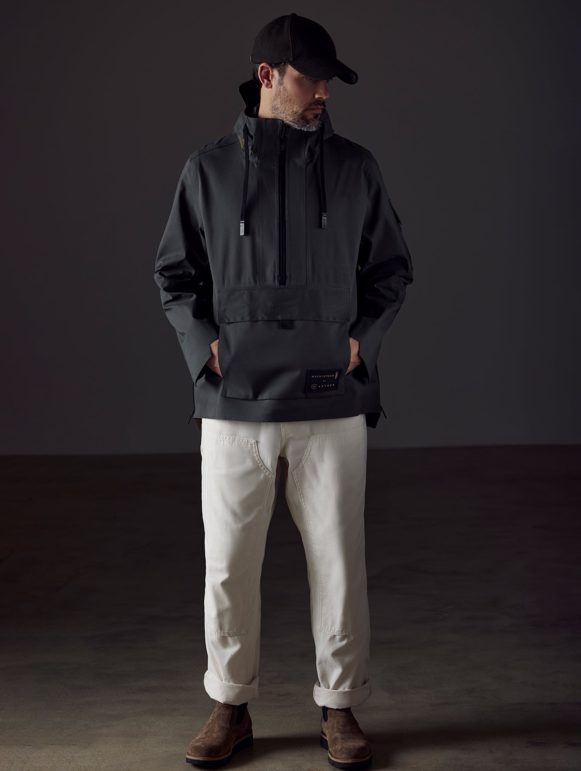 Front full-body view of man wearing AETHER + Mackintosh Field Anorak in Dark Bottle black.