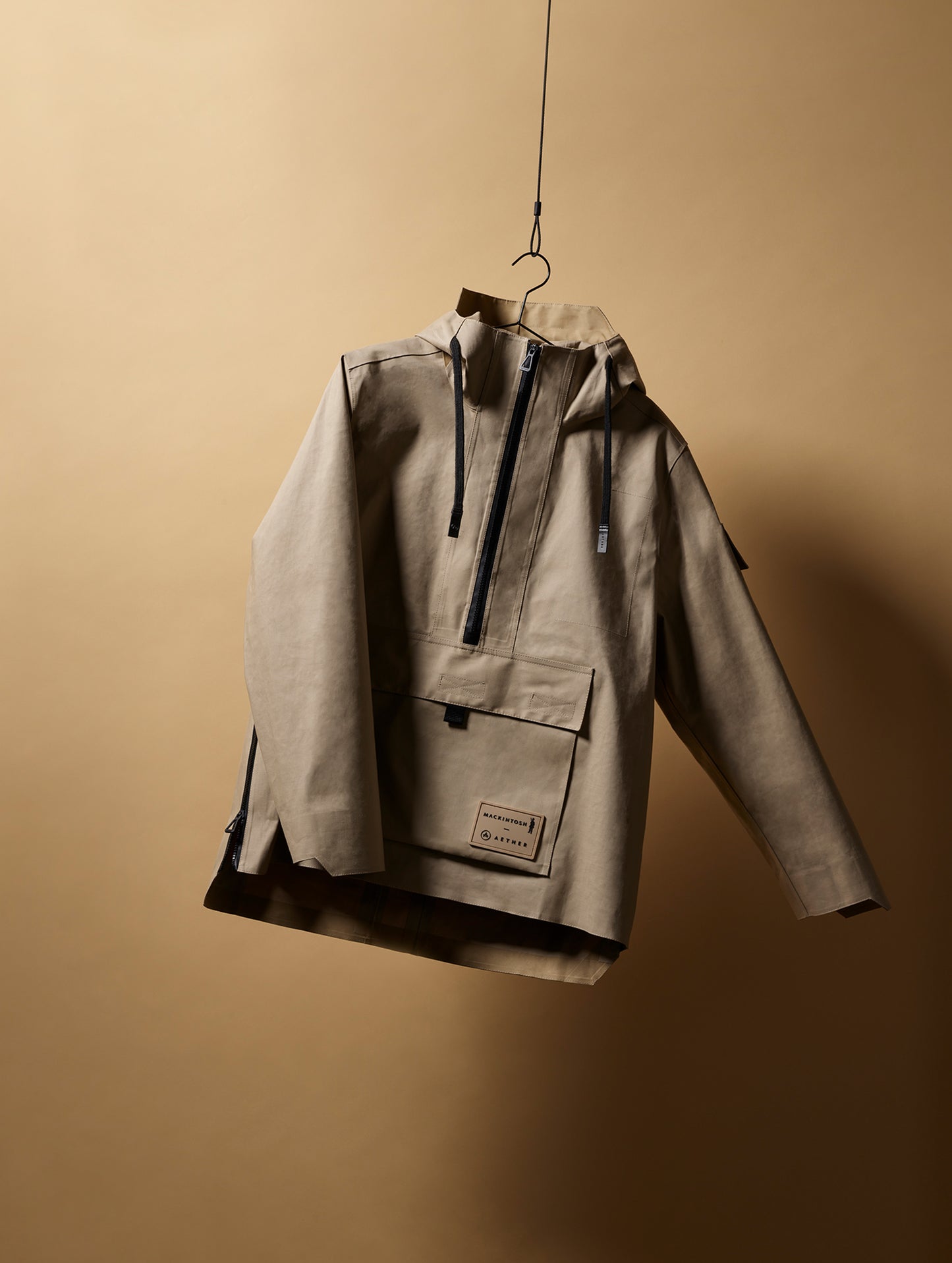 Front view of AETHER + Mackintosh Field Anorak in Fawn light beige on hanger.