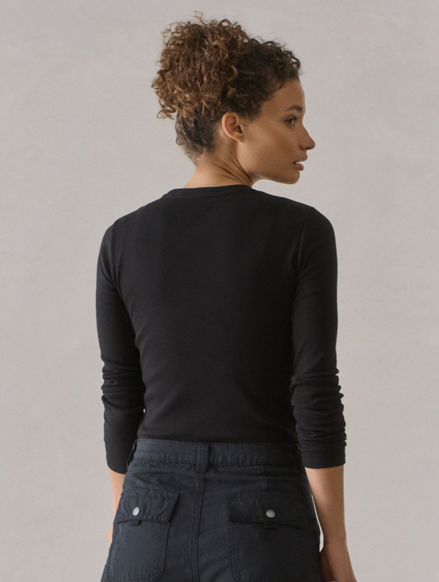 Rear view of woman wearing Amara Long-Sleeve Crew in Onyx Black from AETHER Apparel.