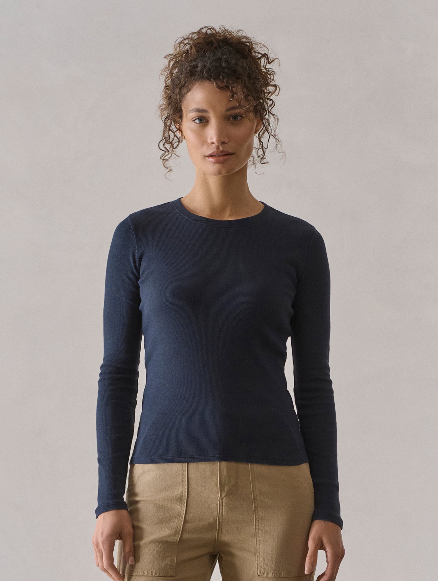 Front view of woman wearing Amara Long-Sleeve Crew in Total Eclipse dark blue from AETHER Apparel.