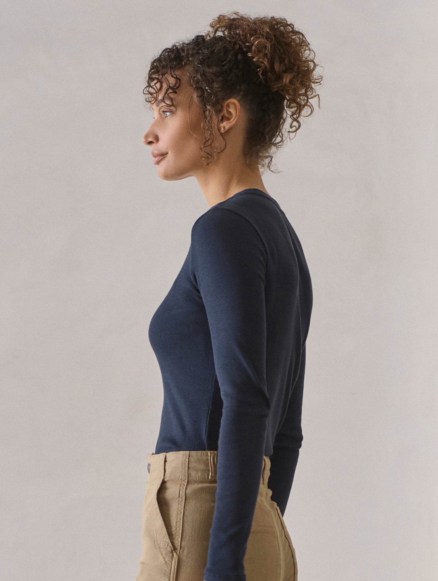 Side profile view of woman wearing Amara Long-Sleeve Crew in Total Eclipse dark blue from AETHER Apparel.