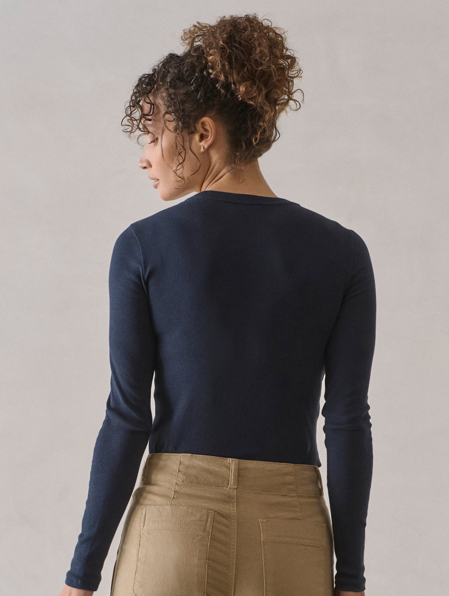 Rear view of woman wearing Amara Long-Sleeve Crew in Total Eclipse dark blue from AETHER Apparel.