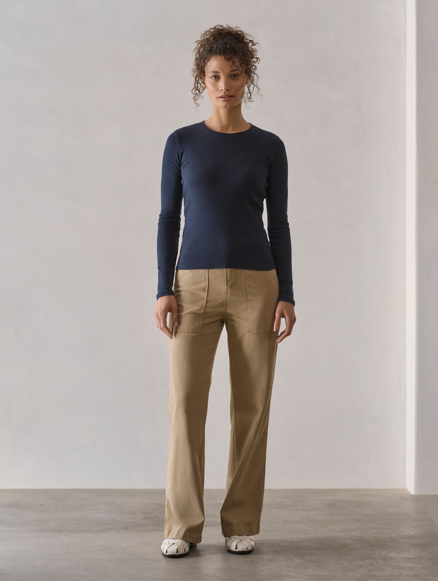 Front full-body view of woman wearing Amara Long-Sleeve Crew in Total Eclipse dark blue from AETHER Apparel.