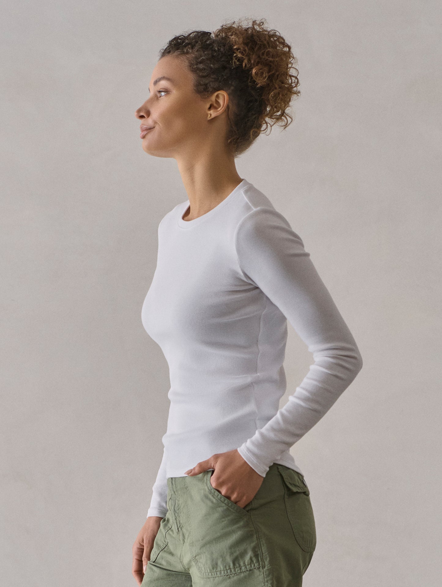 Side profile view of woman wearing Amara Long-Sleeve Crew in White from AETHER Apparel.