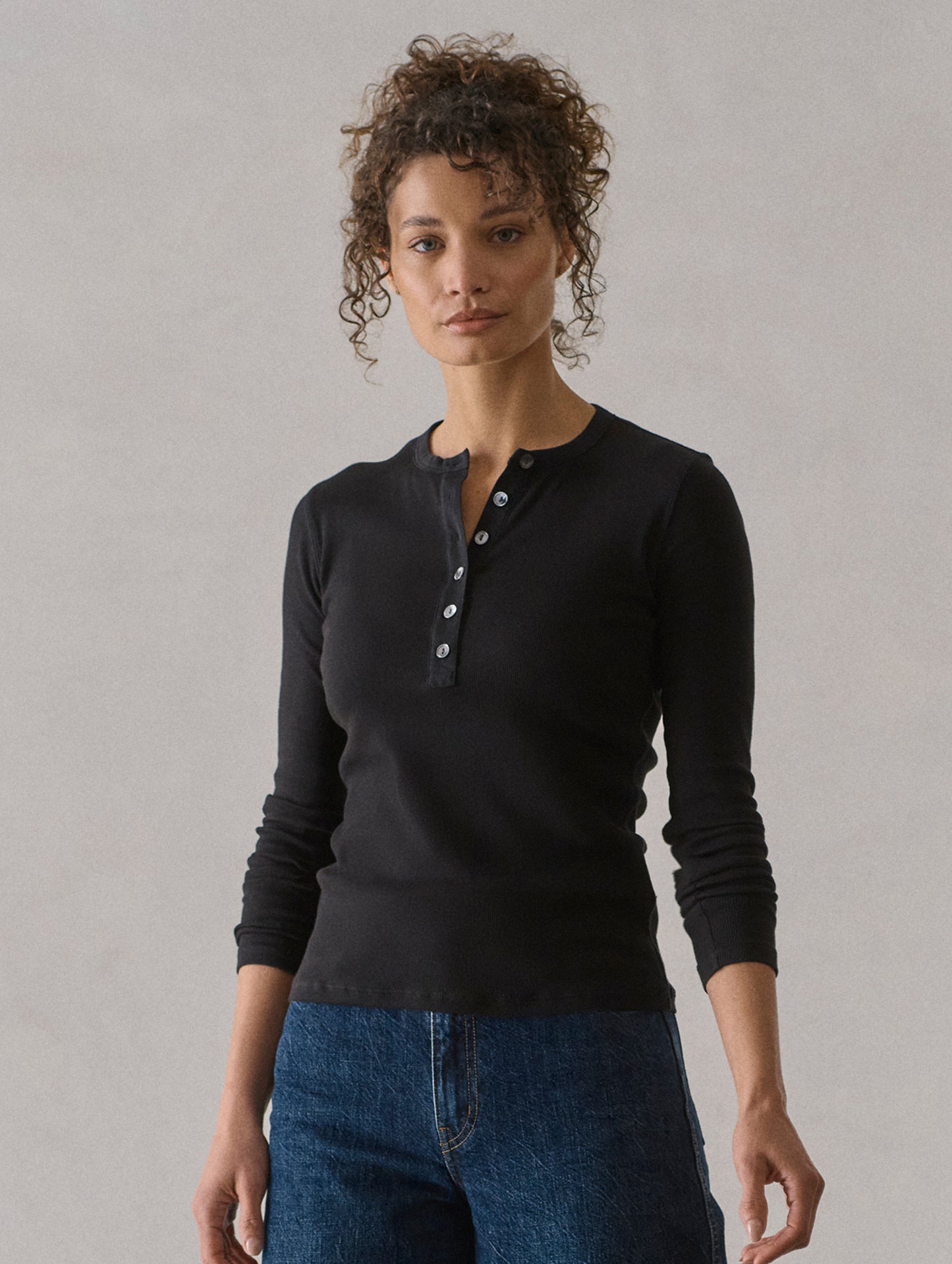 Front view of woman wearing Amara Long-Sleeve Ribbed Henley in Onyx Black from AETHER Apparel.