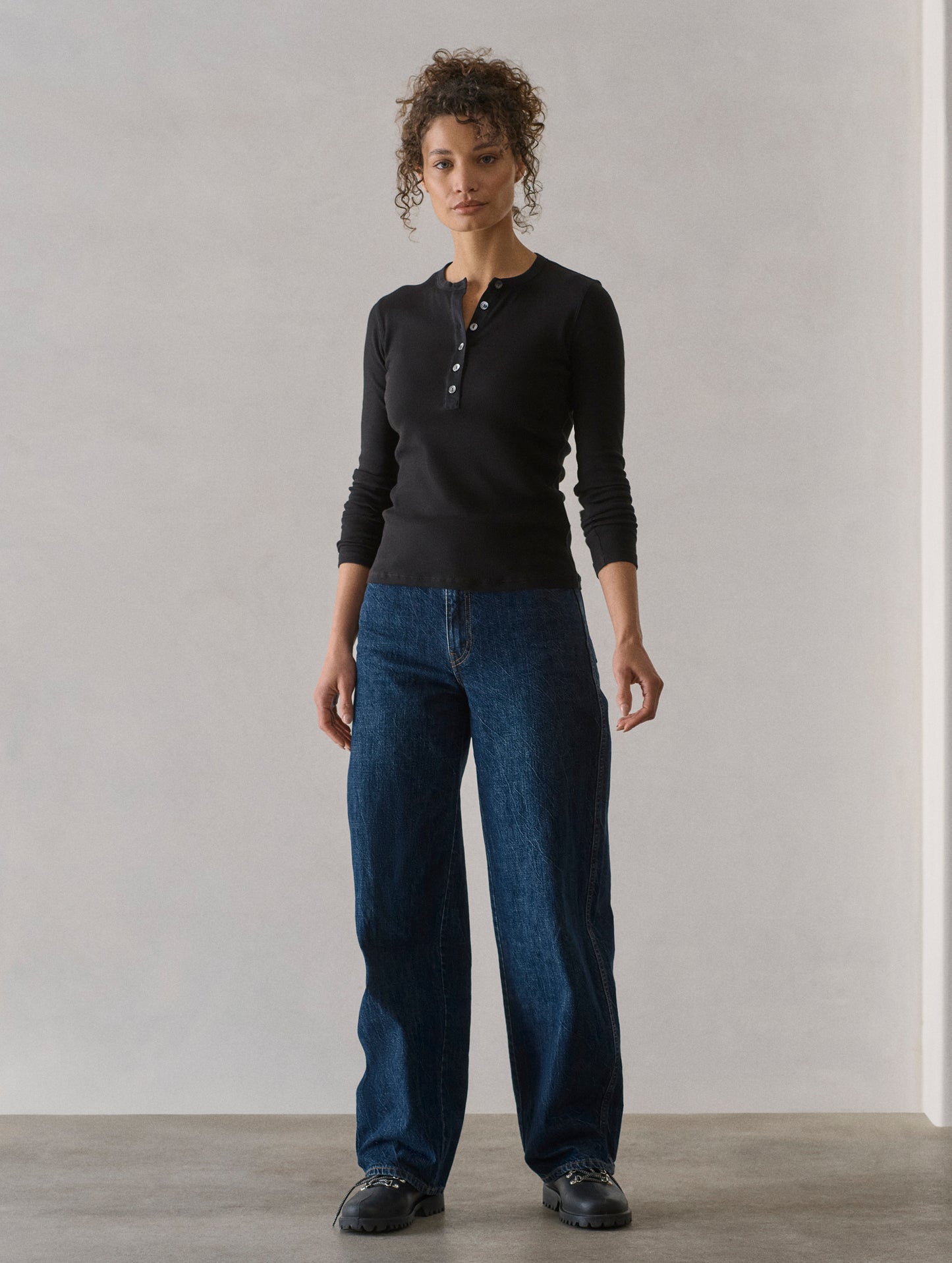 Front full-body view of woman wearing Amara Long-Sleeve Ribbed Henley in Onyx Black from AETHER Apparel.
