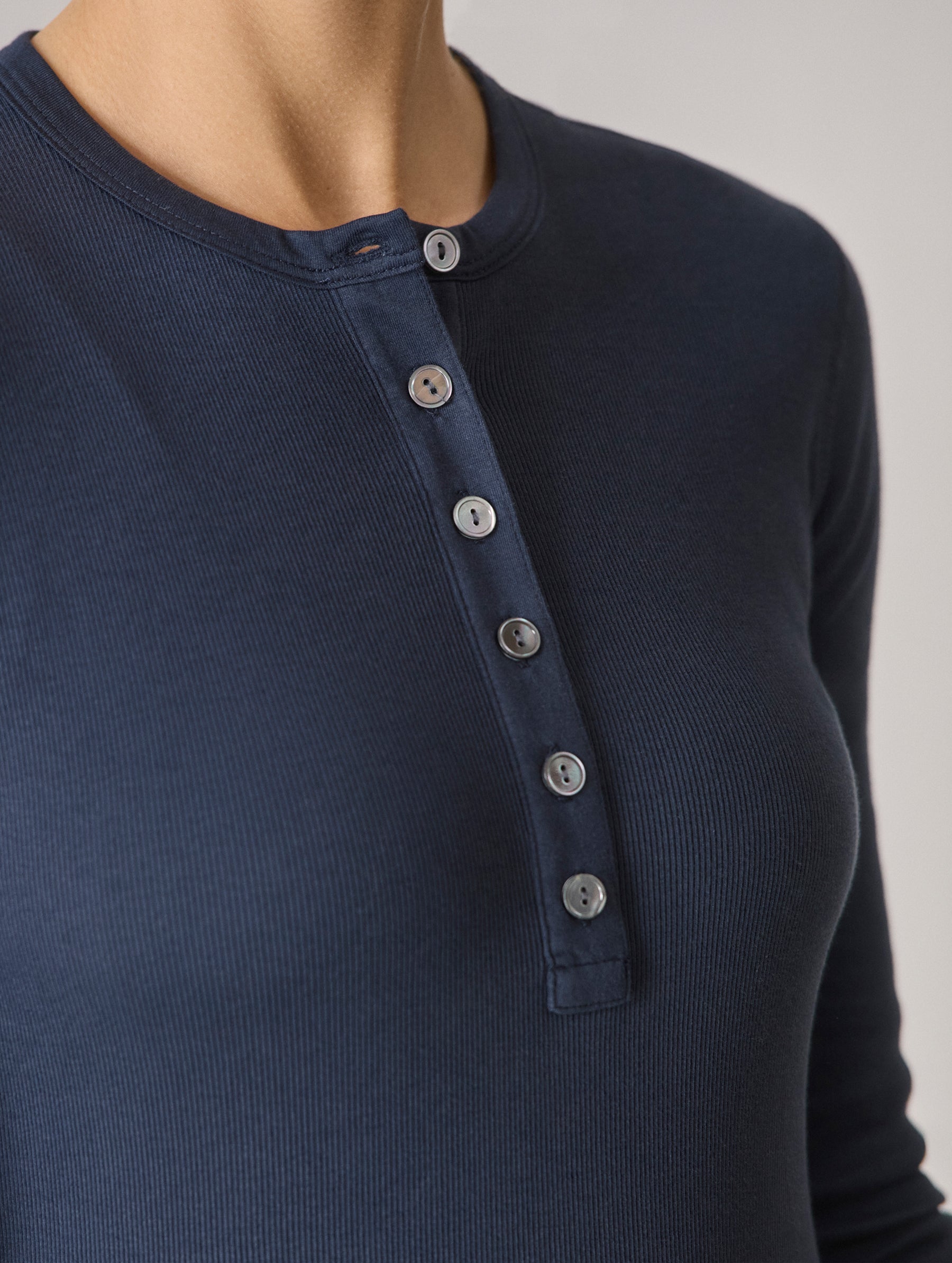Closeup detailed image of the six-button front closure on the Amara Long-Sleeve Ribbed Henley in Total Eclipse dark blue from AETHER Apparel.