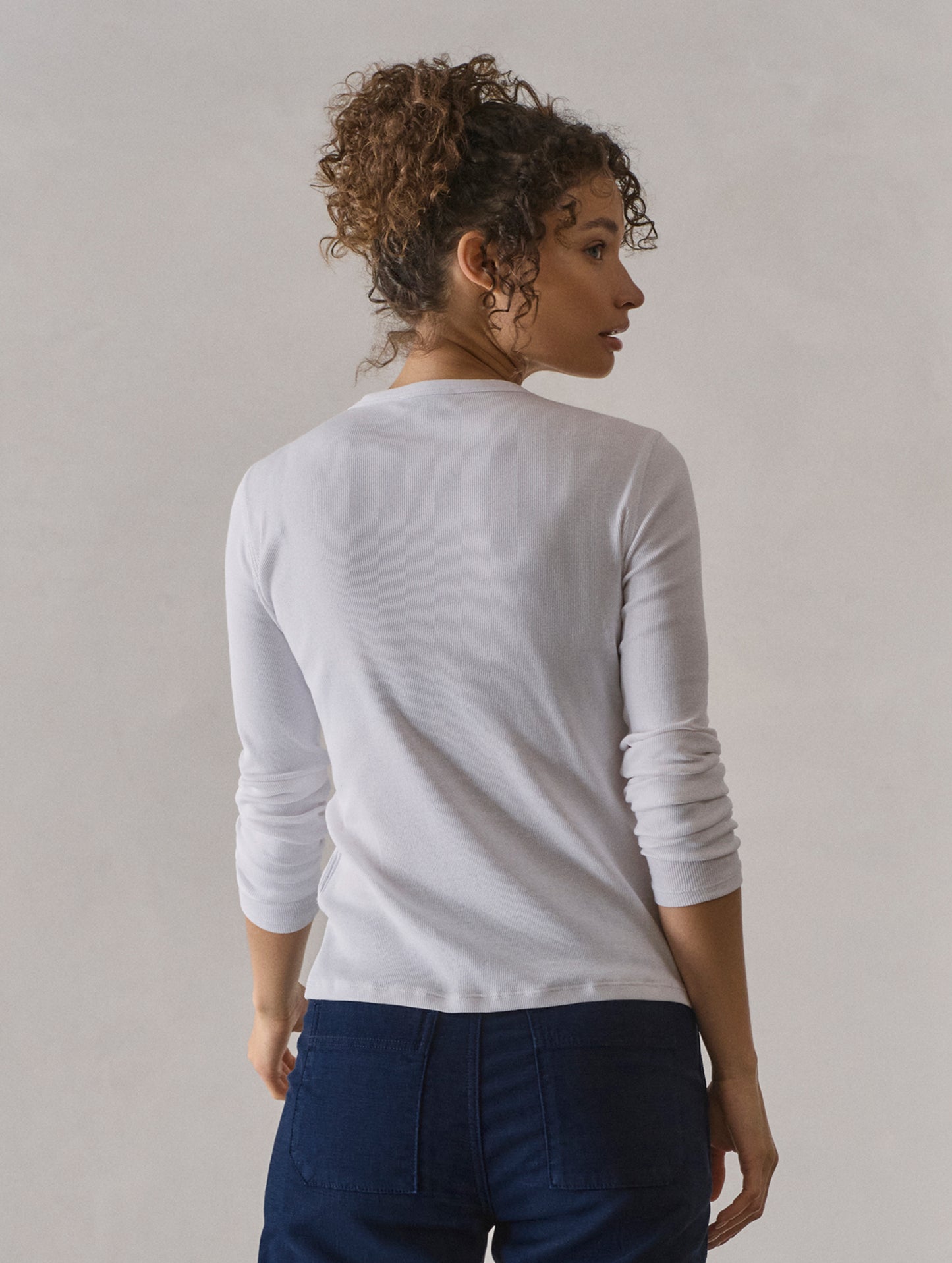 Rear view of woman wearing Amara Long-Sleeve Ribbed Henley in White from AETHER Apparel.