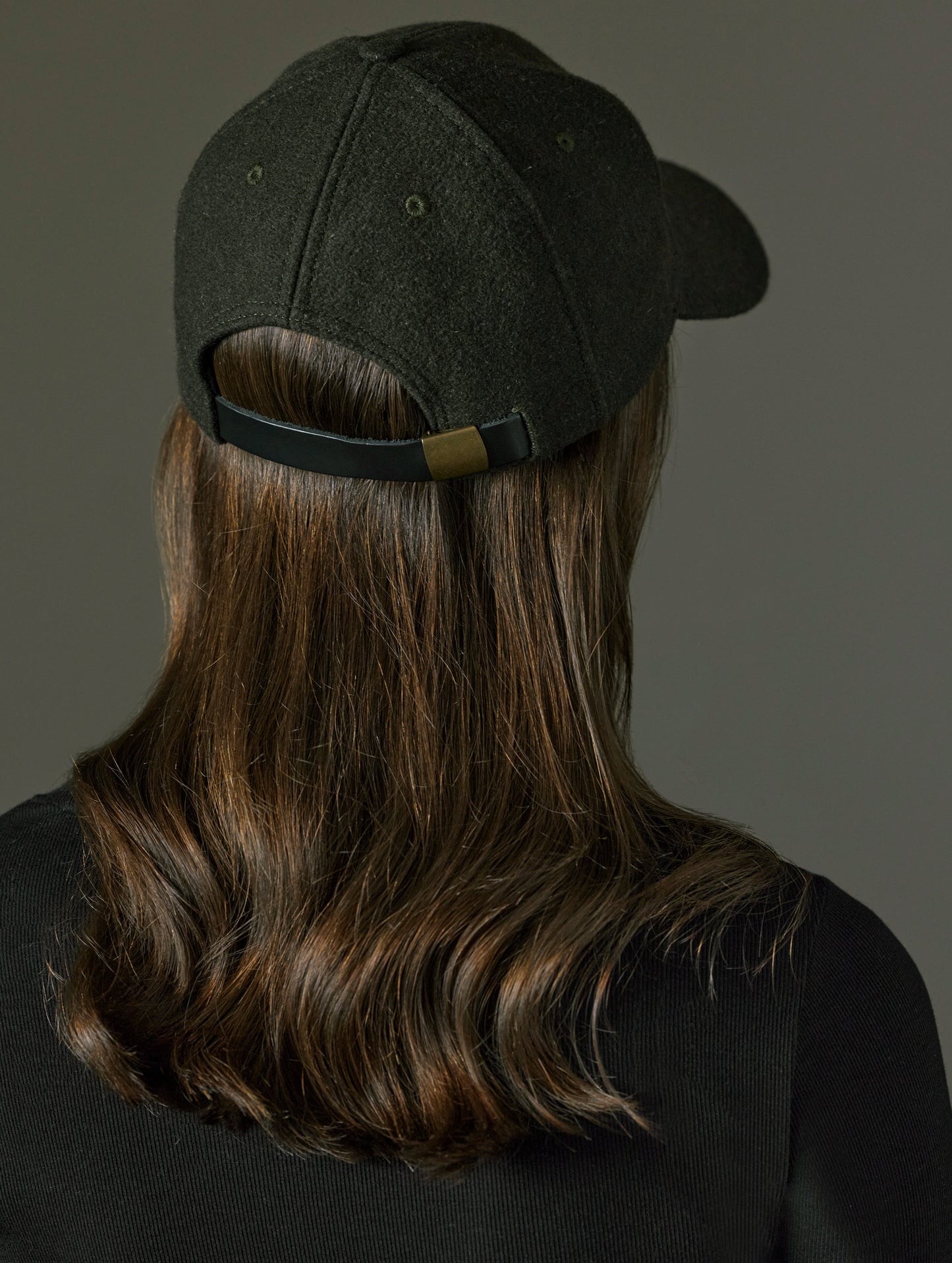 Rear angled view of woman wearing AETHER Wool Hat in Dark Command Green from AETHER Apparel.