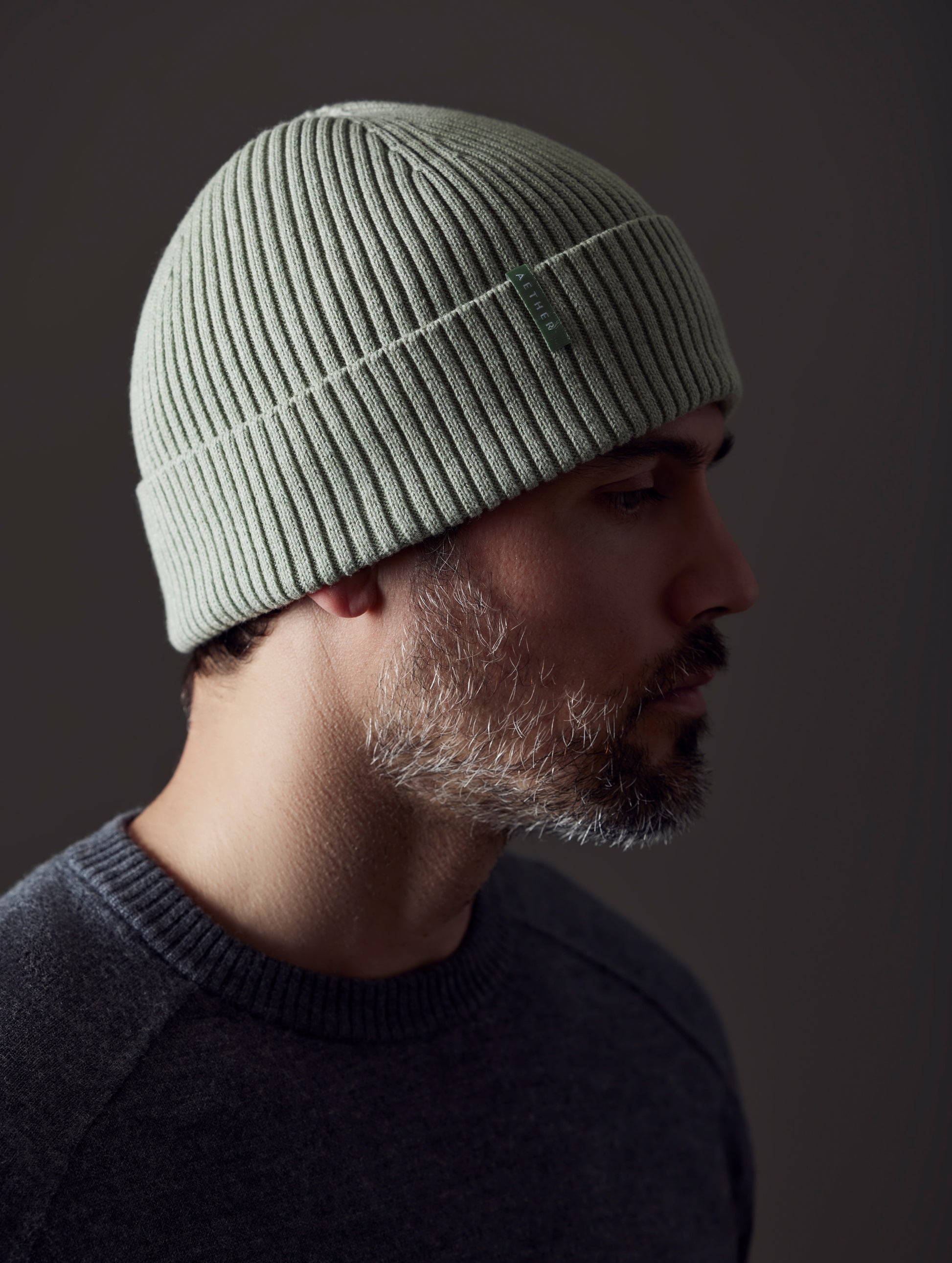 Front angled view of man wearing Chalet Cotton Beanie in Mineral Green Heather from AETHER Apparel.