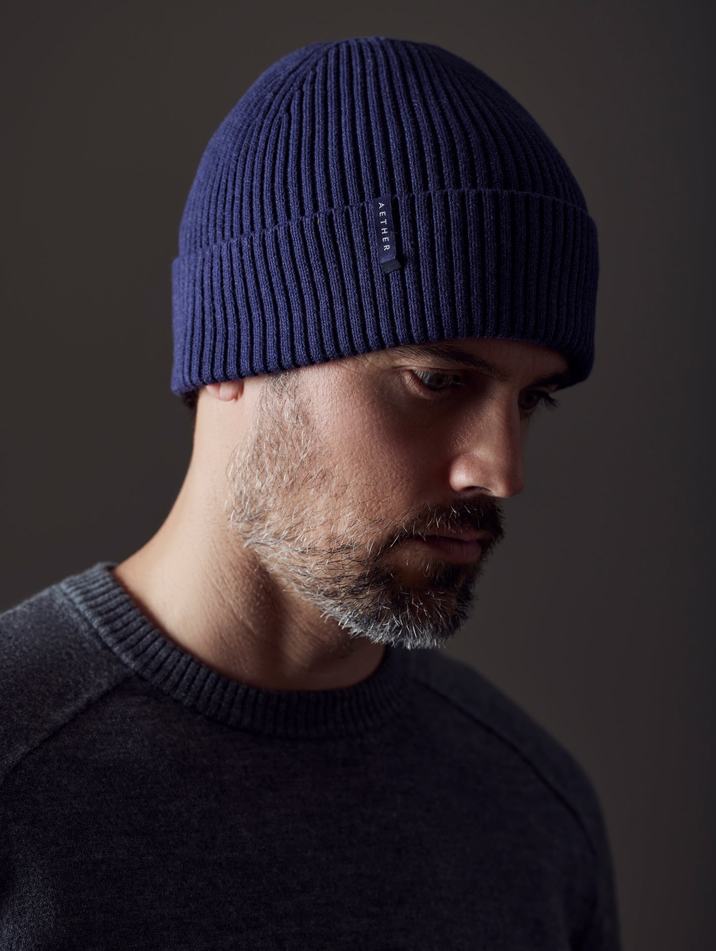 Front angled view of man wearing Chalet Cotton Beanie in Total Eclipse dark blue from AETHER Apparel.
