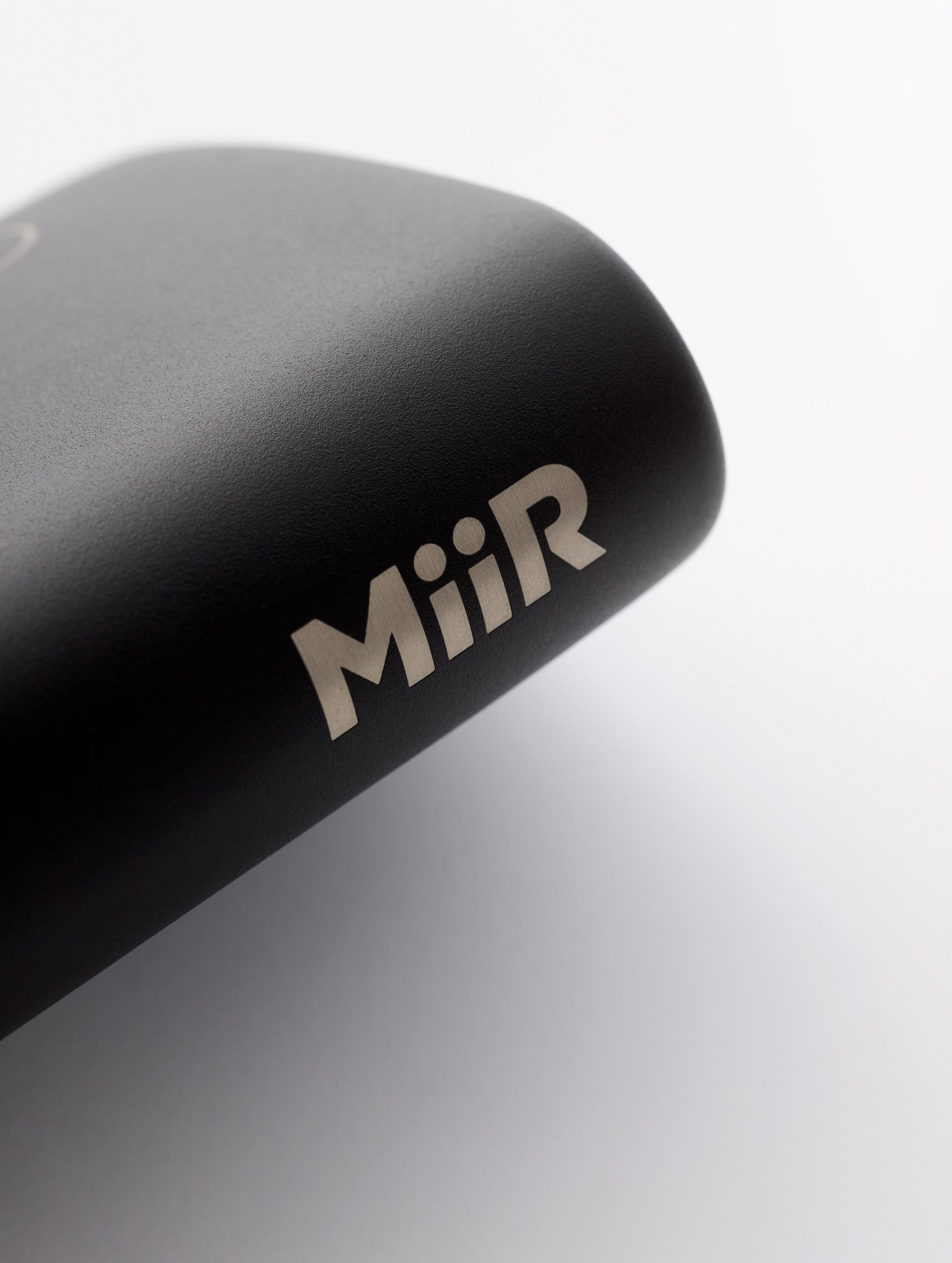 Closeup detailed view of MiiR logo on side of AETHER + Miir Aero Flask in Black with top open.