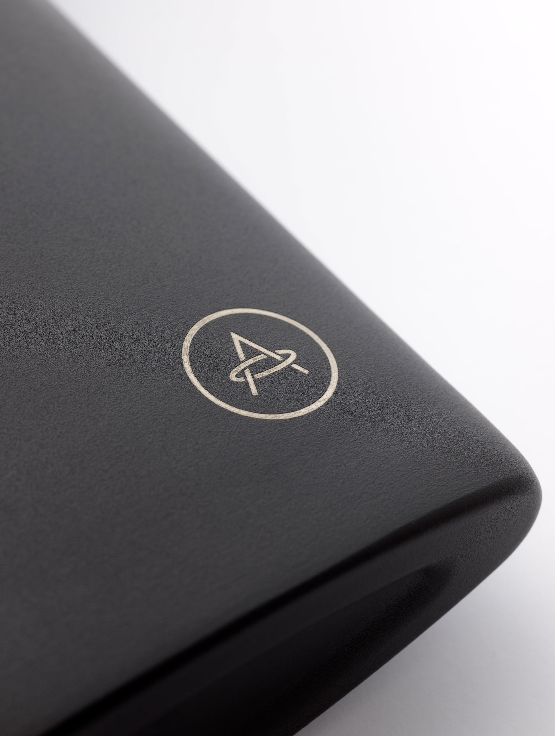 Closeup detailed view of AETHER logo on bottom corner of AETHER + Miir Aero Flask in Black with top open.