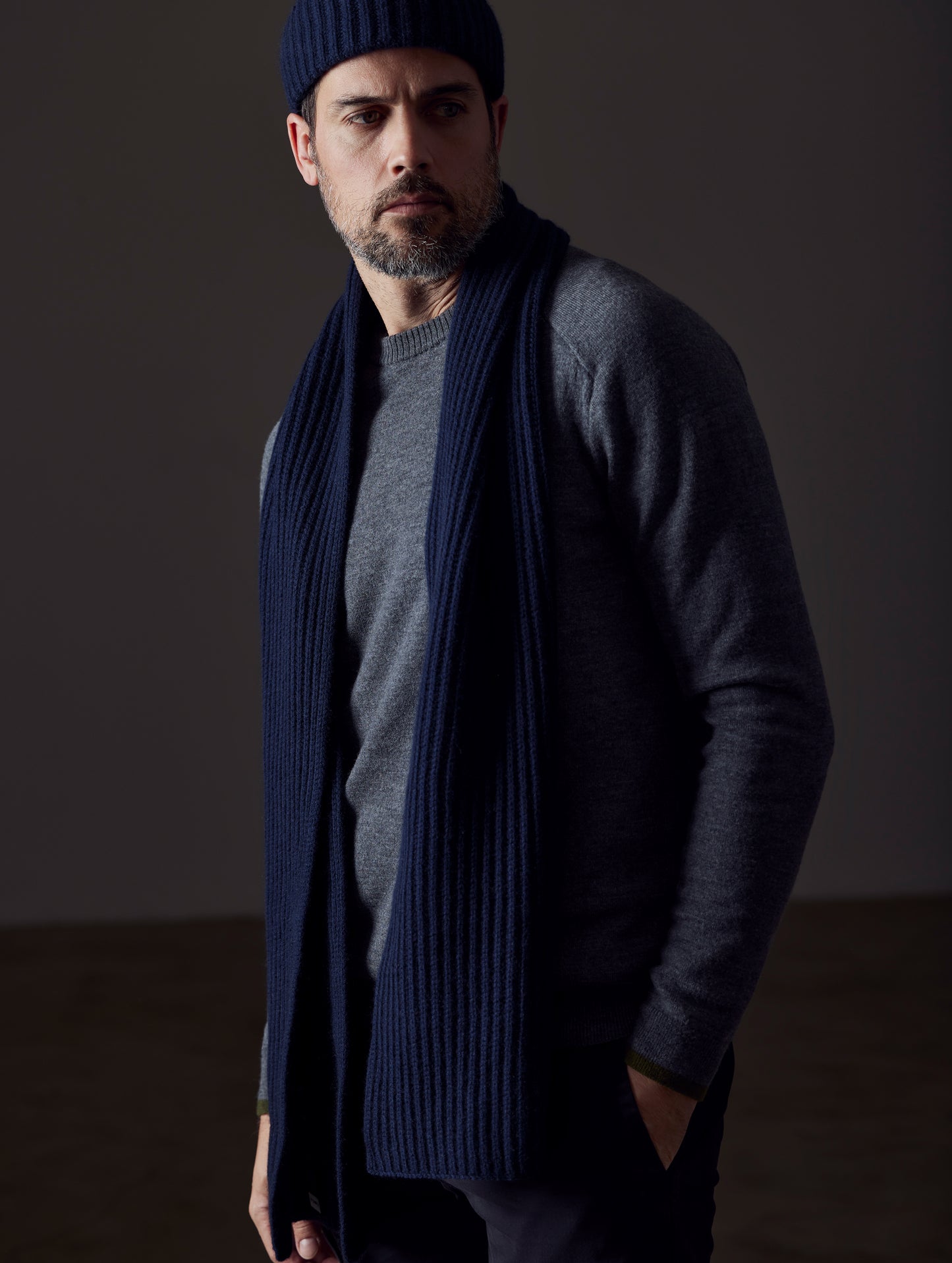 Front angled view of man wearing Ribbed Cashmere Scarf in Total Eclipse dark blue from AETHER Apparel.