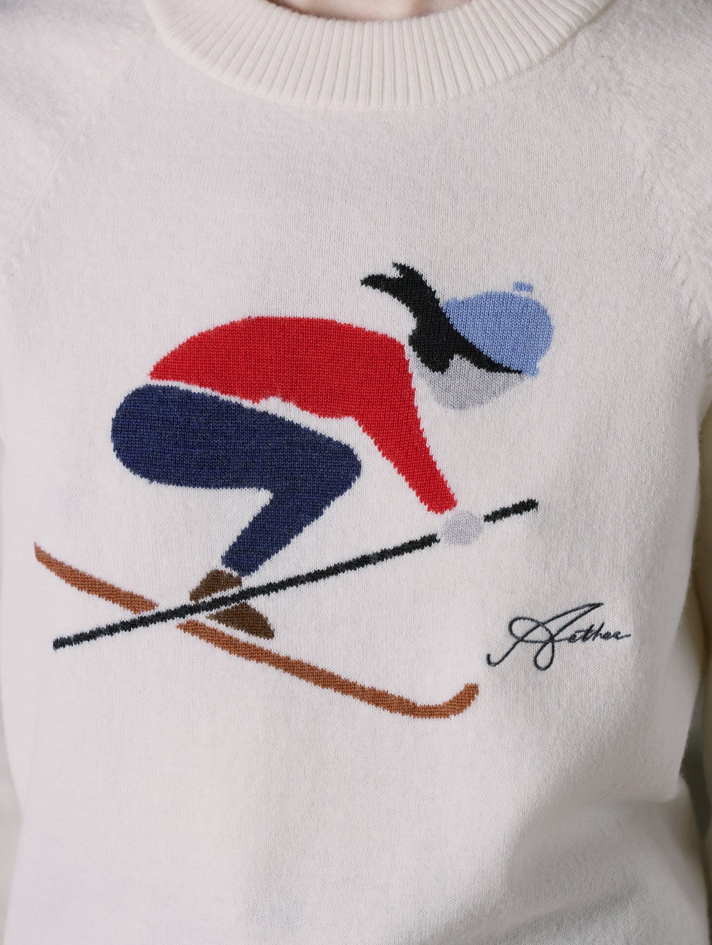 Closeup detailed view of jacquard downhill skier design on front of women’s Bridget Sweater in Winter White from AETHER Apparel.