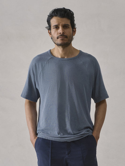 Front upper-body view of man wearing Buckhorn Cotton Raglan Tee 2.0 in Portal Blue from AETHER Apparel.