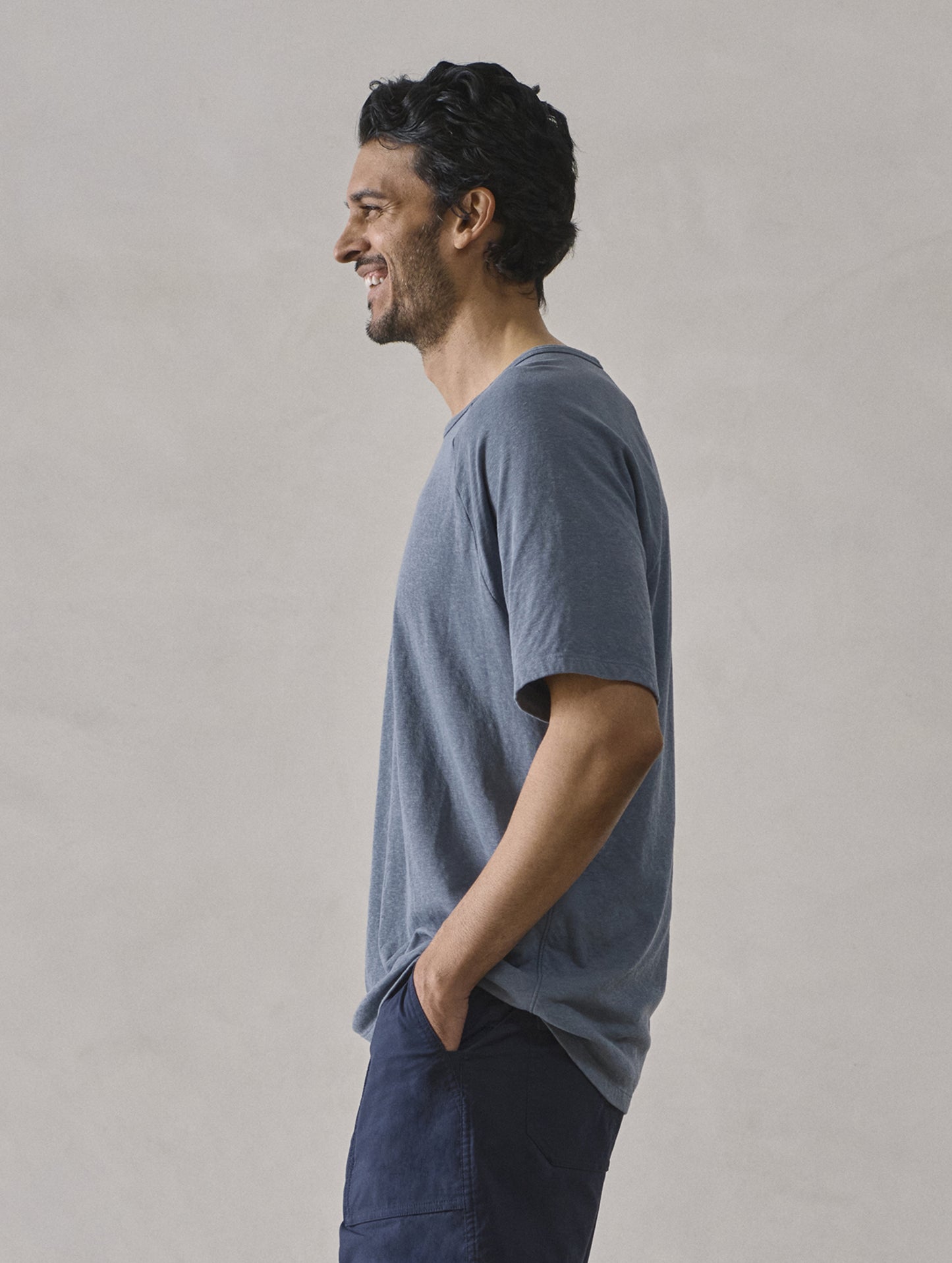 Side profile upper-body view of man wearing Buckhorn Cotton Raglan Tee 2.0 in Portal Blue from AETHER Apparel.