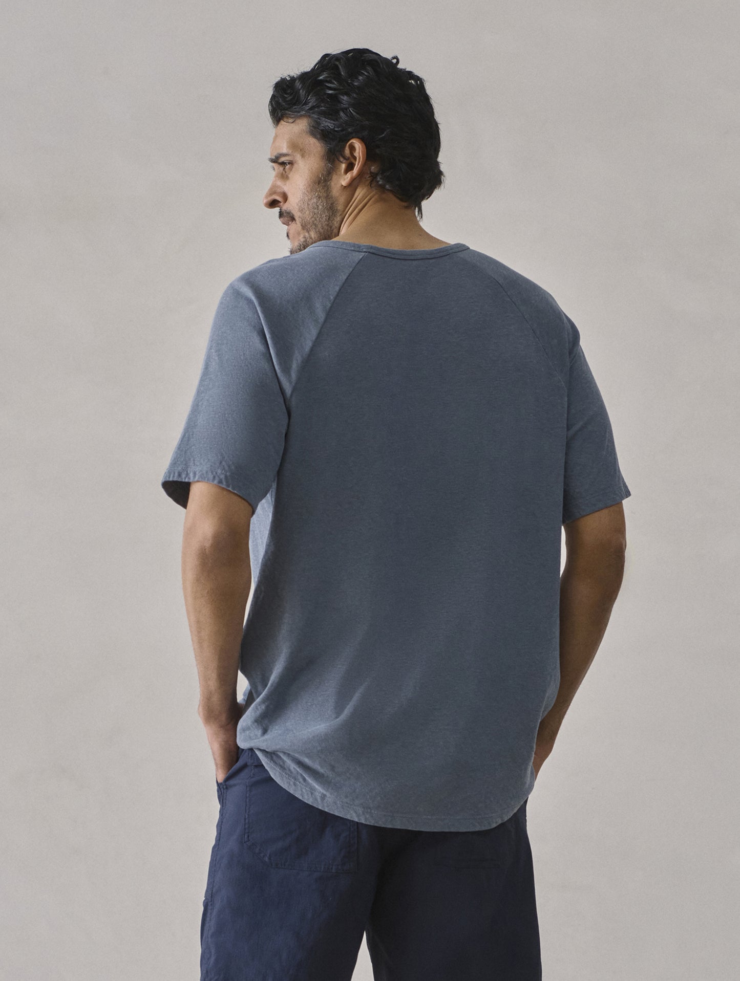 Rear upper-body view of man wearing Buckhorn Cotton Raglan Tee 2.0 in Portal Blue from AETHER Apparel.