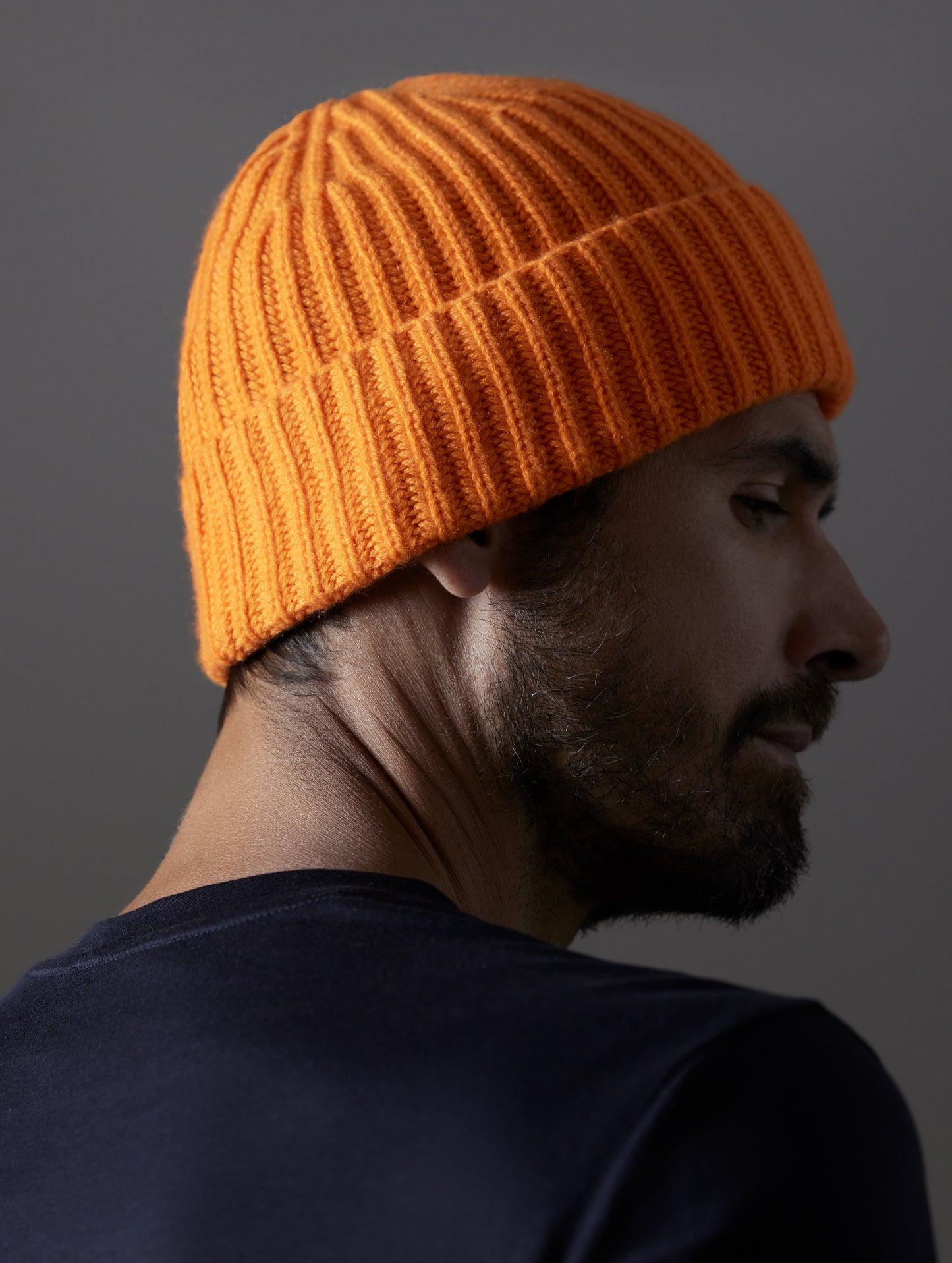 Rear angled view of man wearing Cashmere Hat in Bitter Orange from AETHER Apparel.