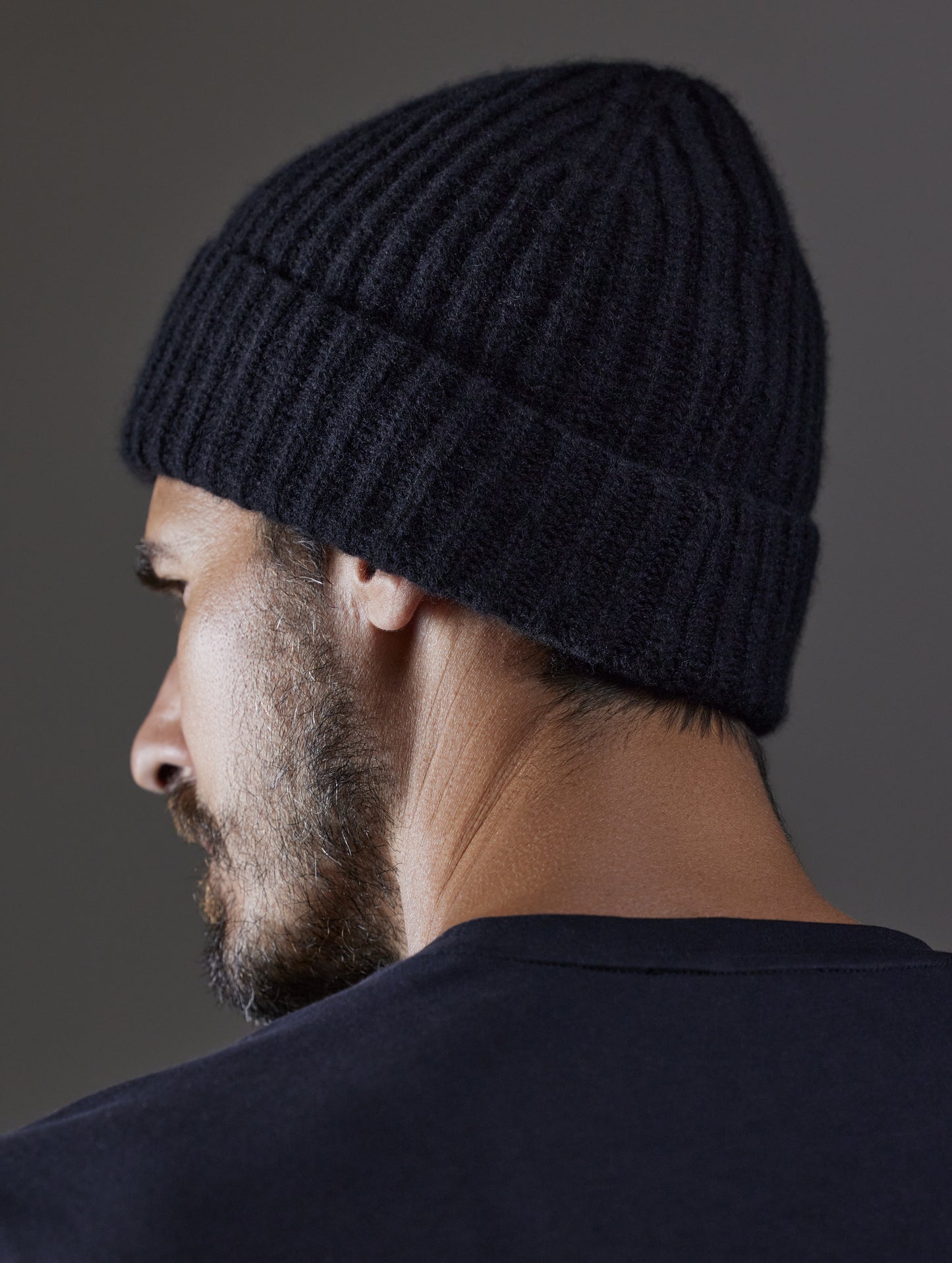 Rear angled view of man wearing Cashmere Hat in Onyx Black from AETHER Apparel.