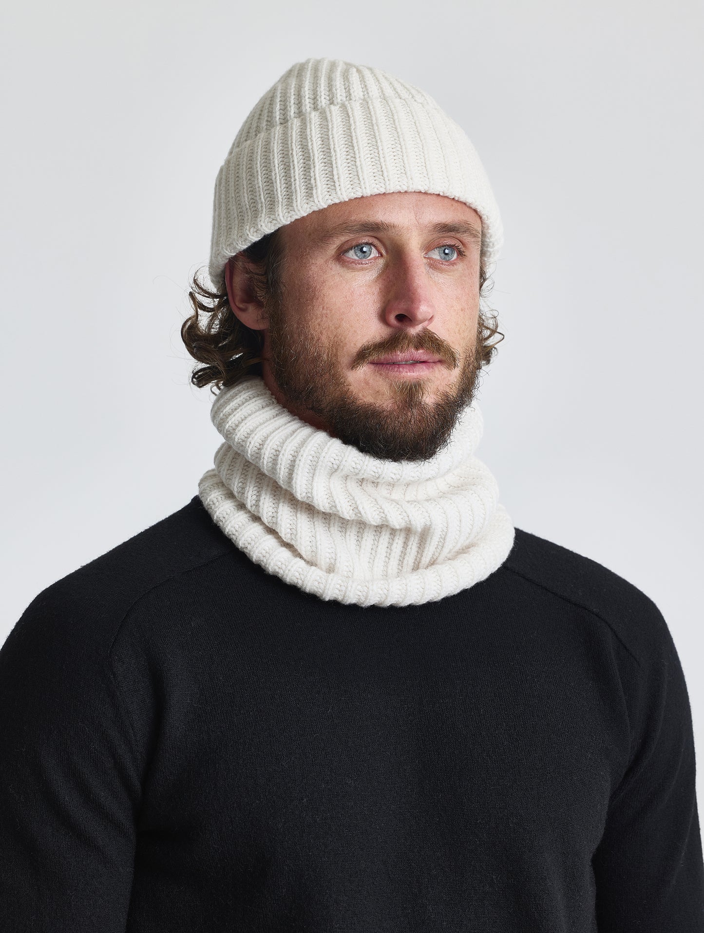 Front angled view of man wearing the Cashmere Hat and the Cashmere Neck Gaiter in Winter White from AETHER Apparel.