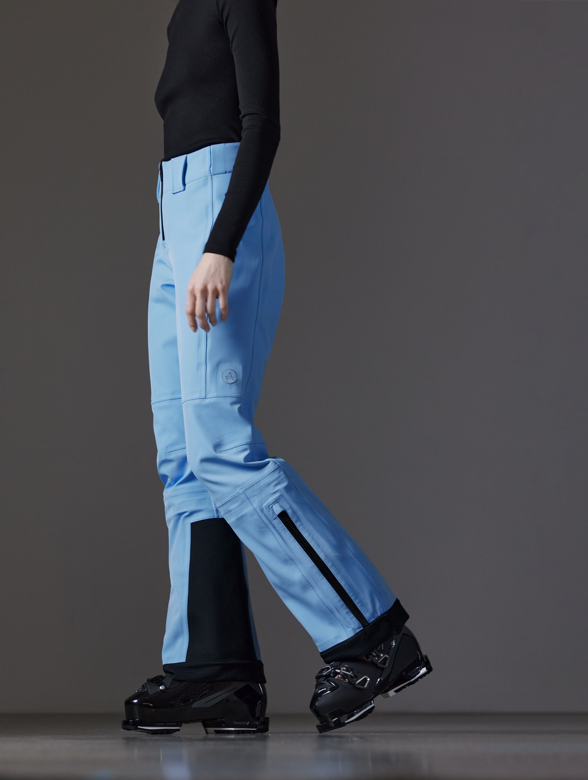 Side profile lower body view of woman wearing Descent Pant in Atlas Blue from AETHER Apparel.