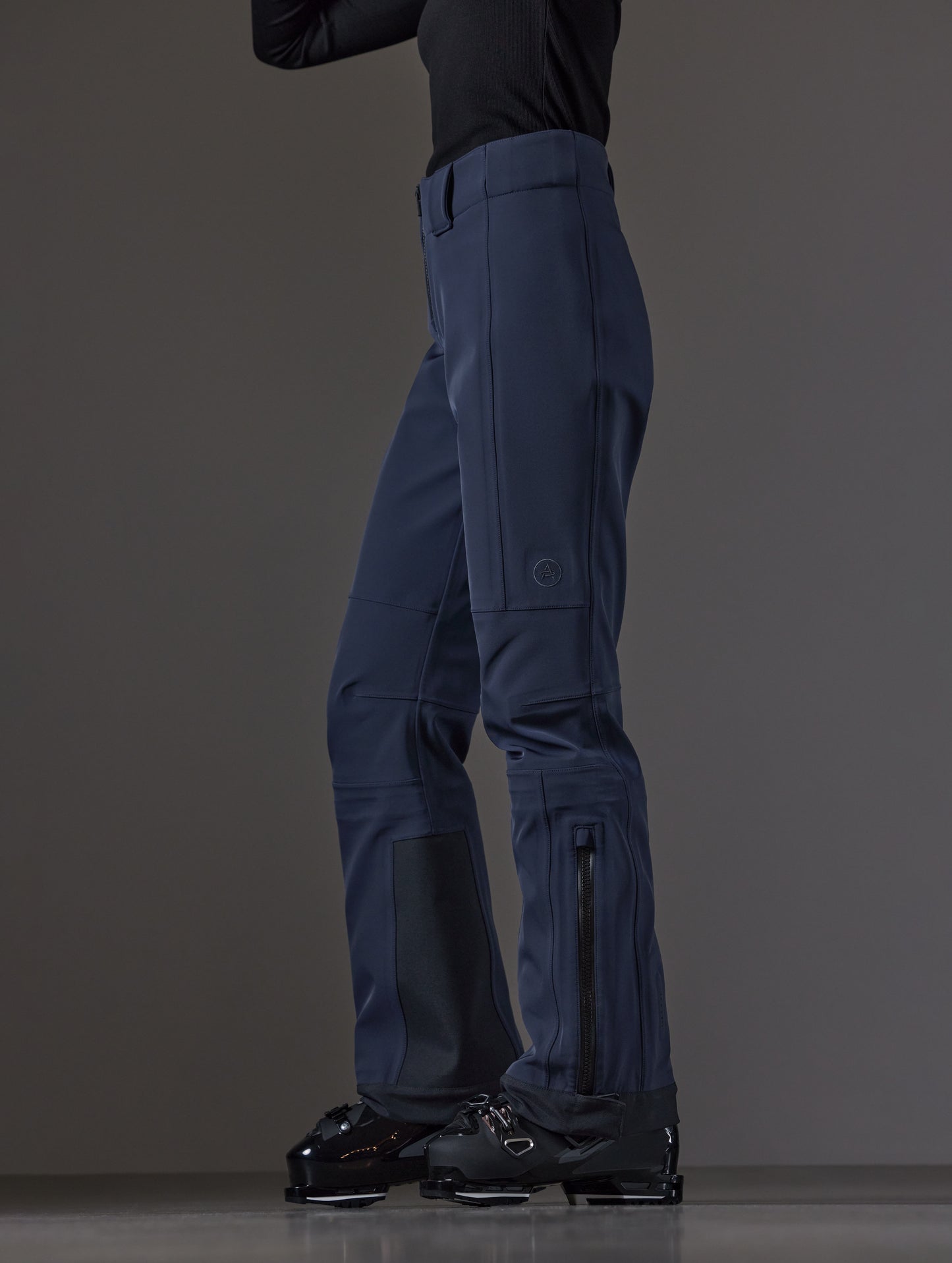 Side profile lower body view of woman wearing Descent Pant in Total Eclipse dark blue from AETHER Apparel.