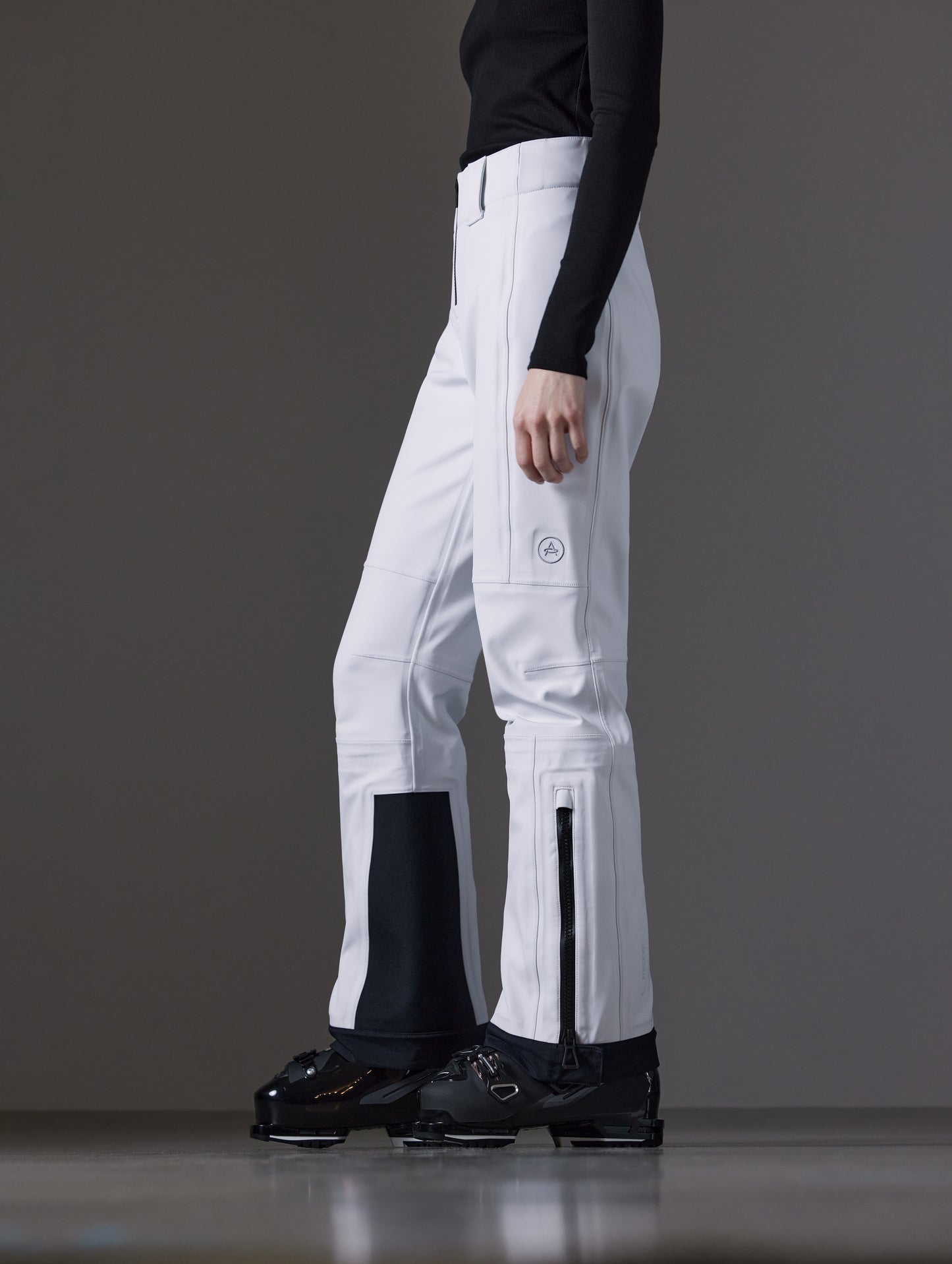 Side profile lower body view of woman wearing Descent Pant in White from AETHER Apparel.