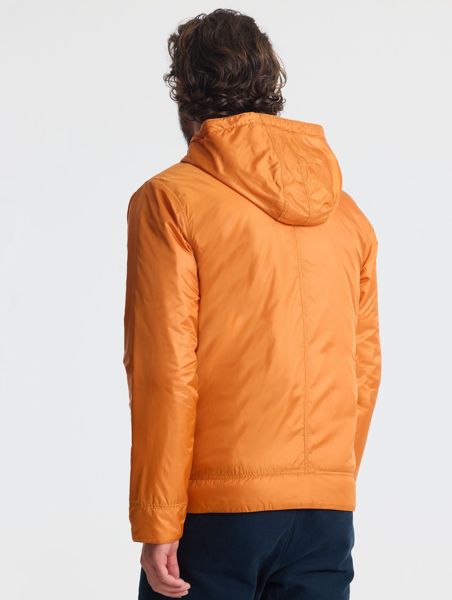 Rear view of man wearing Eco Space Hoodie in Autumn Orange from AETHER Apparel.