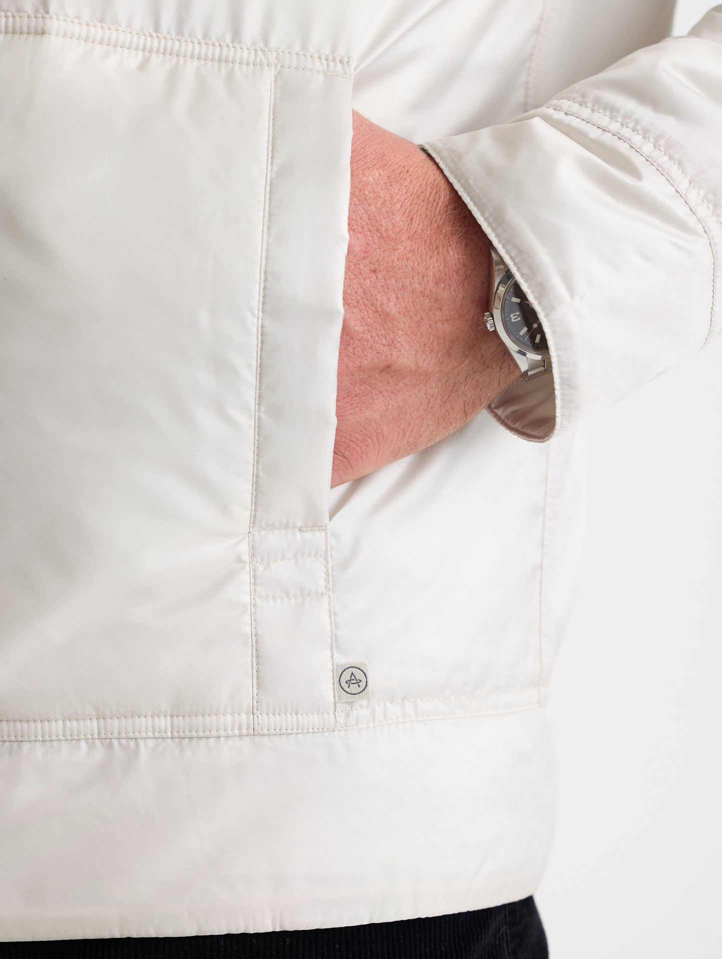 Closeup view of wearer's left hand in pocket of Eco Space Hoodie in Bone white from AETHER Apparel.