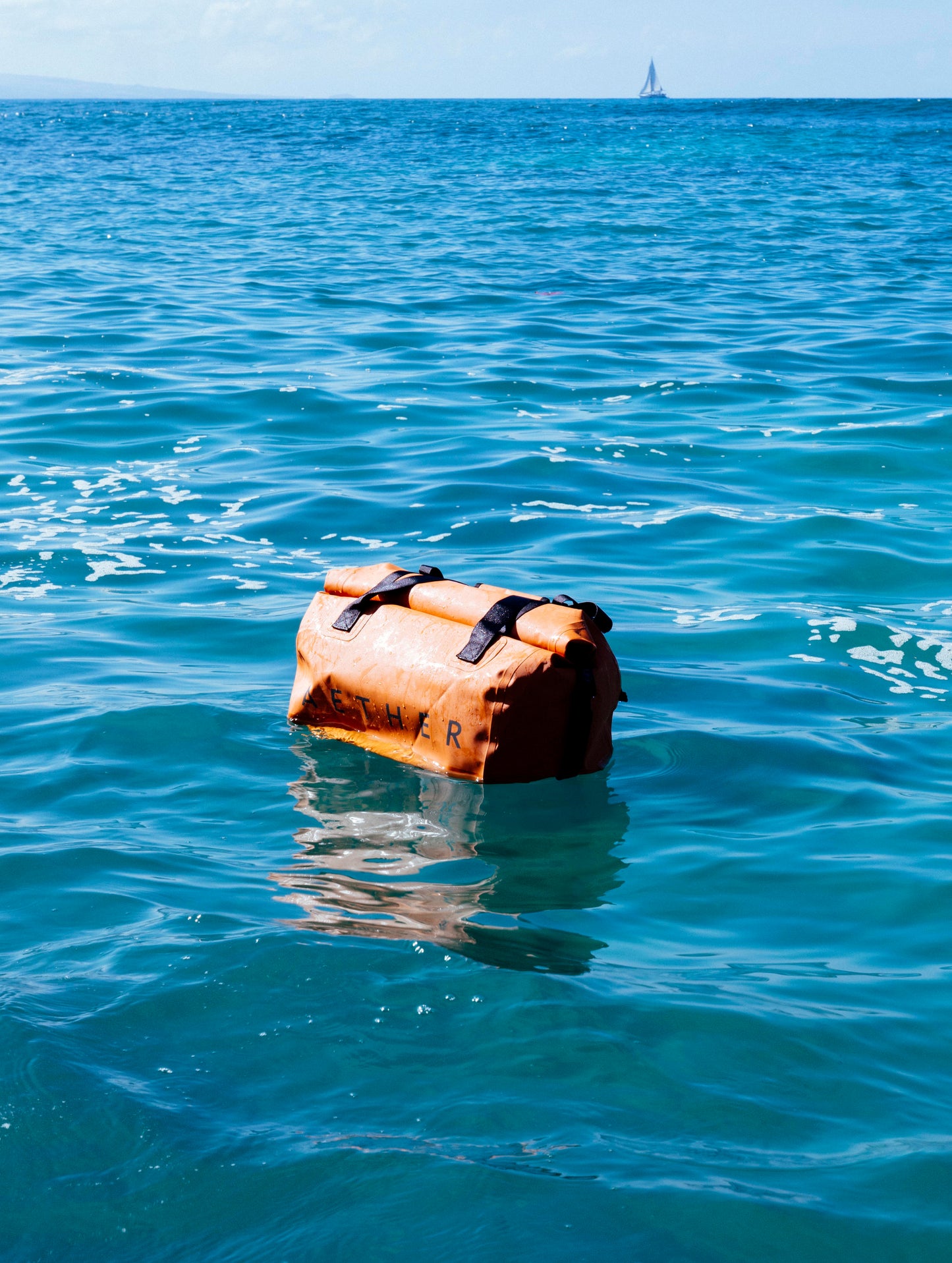 Excursion Duffle Bag 45L in Total Eclipse dark blue from AETHER Apparel floating on top of the ocean.