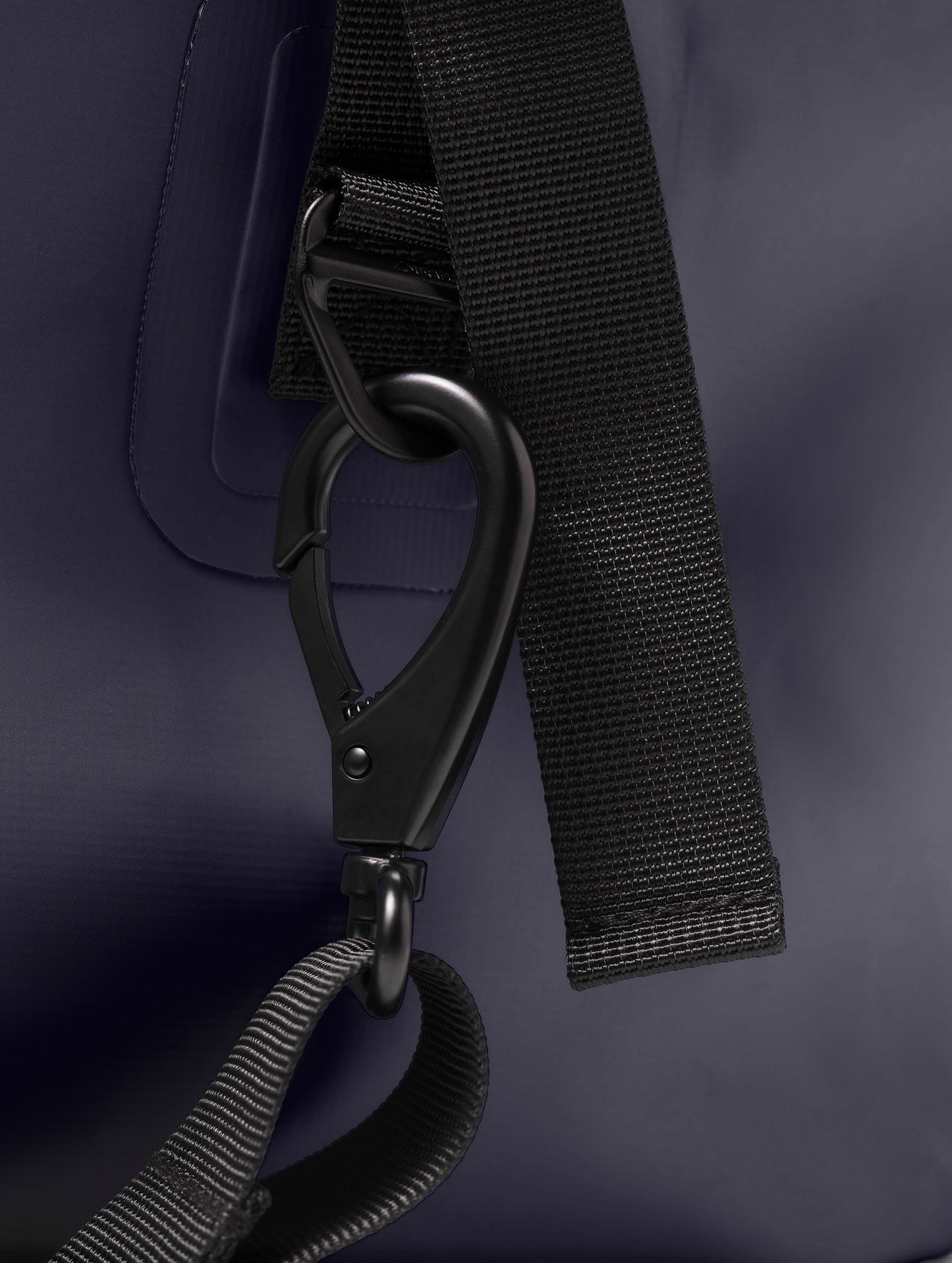 Closeup detailed view of the removable shoulder strap's black hardware on the Excursion Duffle Bag 60L in Total Eclipse dark blue from AETHER Apparel.