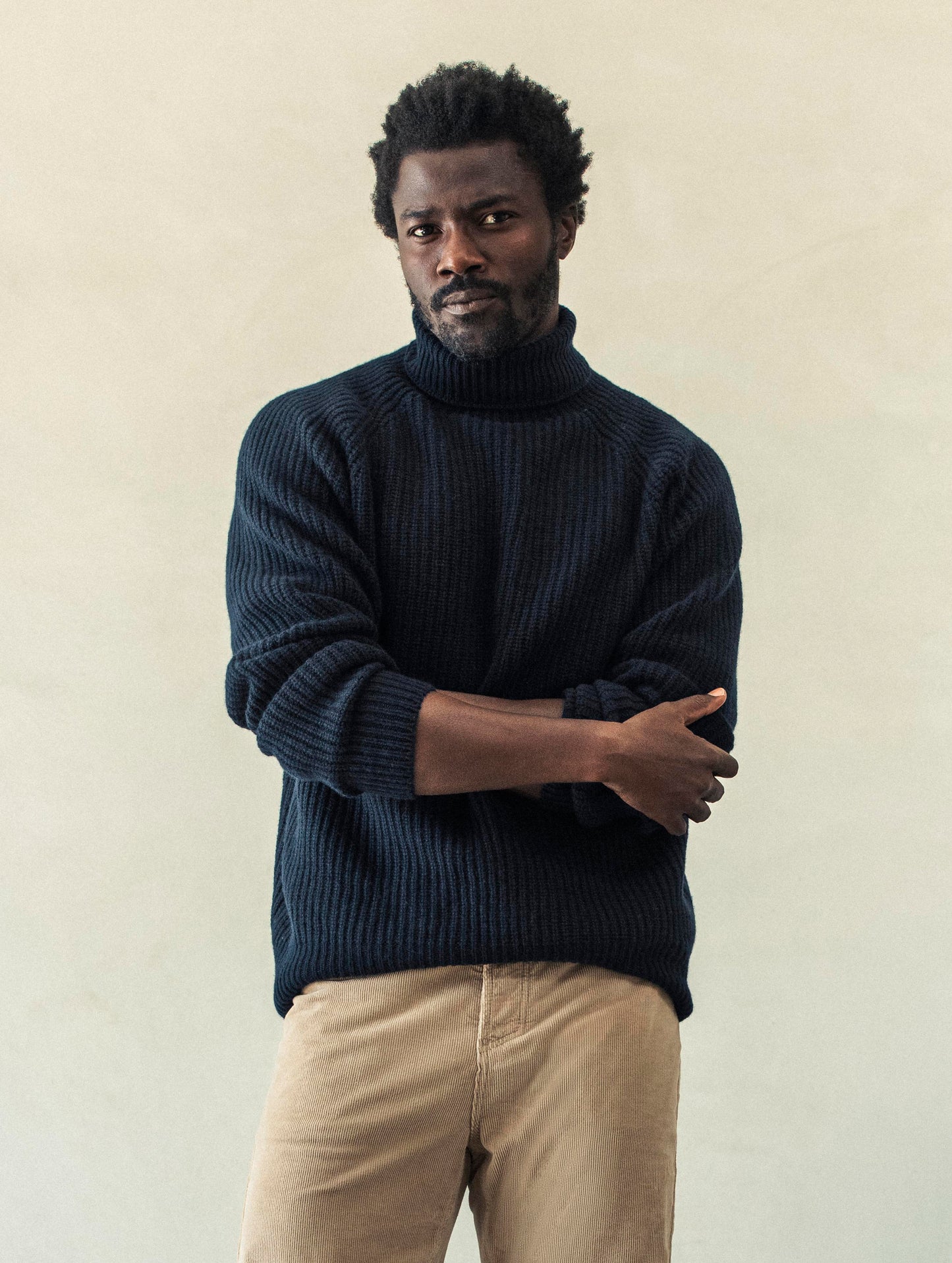 Front view of man with arms crossed wearing Finley Sweater in Total Eclipse dark blue from AETHER Apparel.