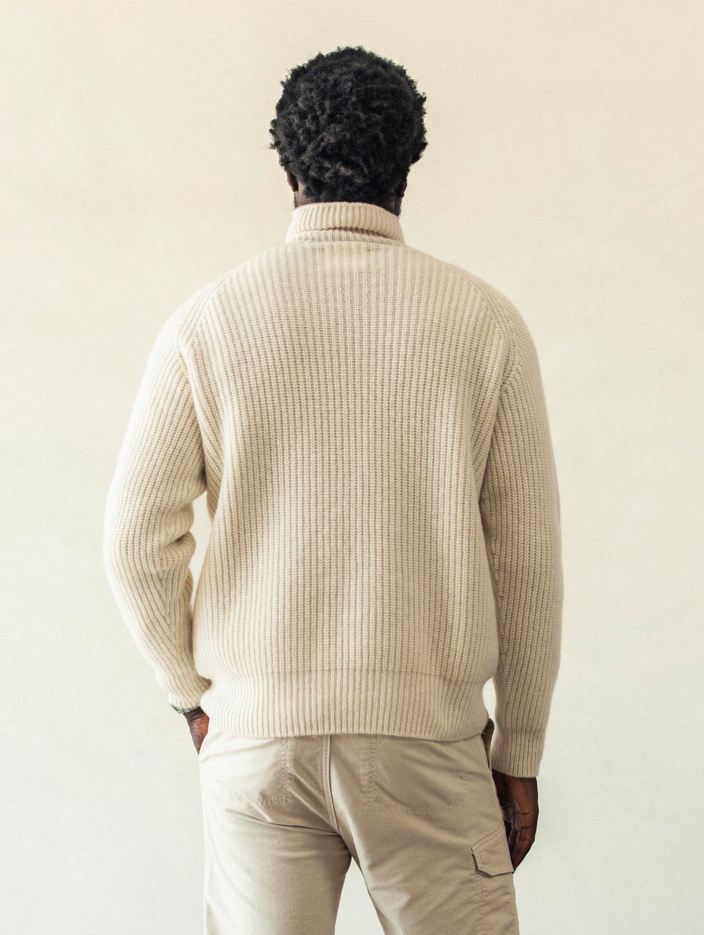Rear view of man with hand in pant pocket wearing Finley Sweater in Winter White from AETHER Apparel.