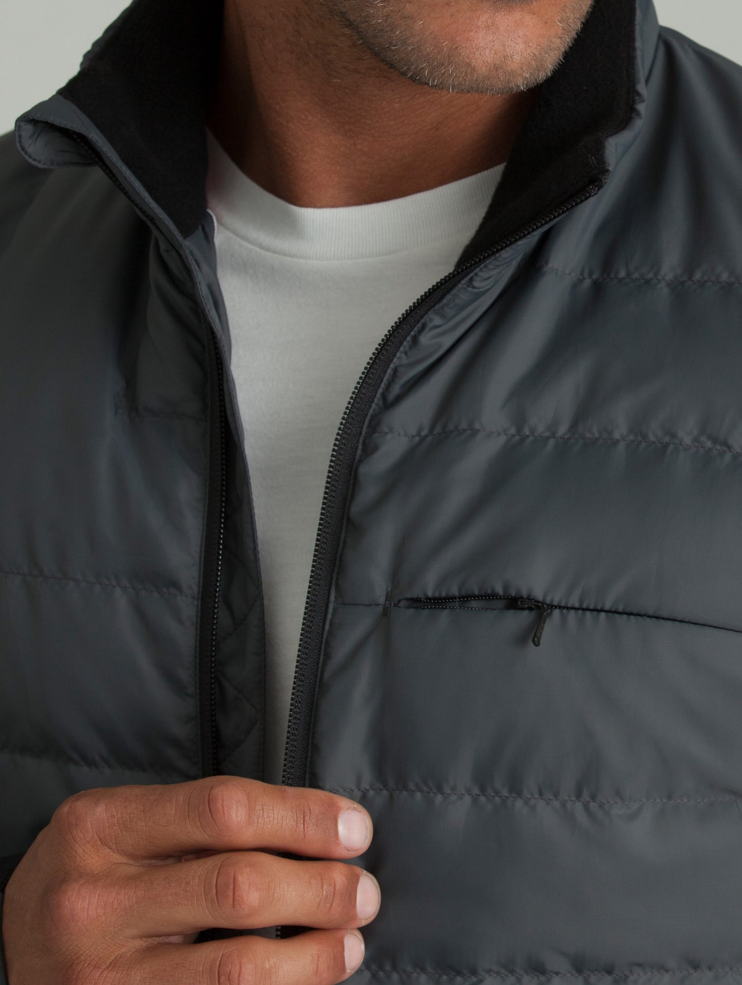 Man wearing grey Ghost Jacket from AETHER Apparel, closely displaying left chest pocket.