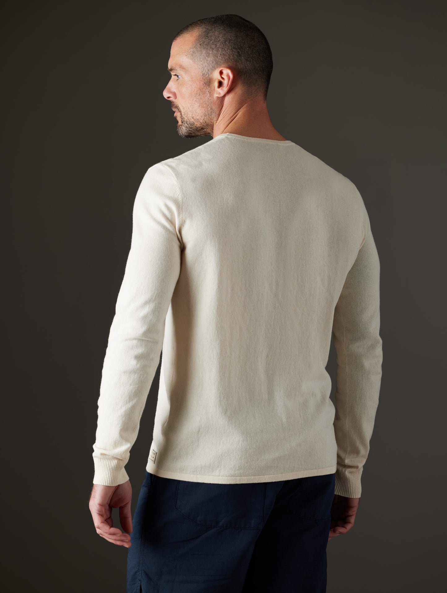 Rear 3/4 body view of man wearing Aero Sweater in Oatmeal Heather from AETHER Apparel.